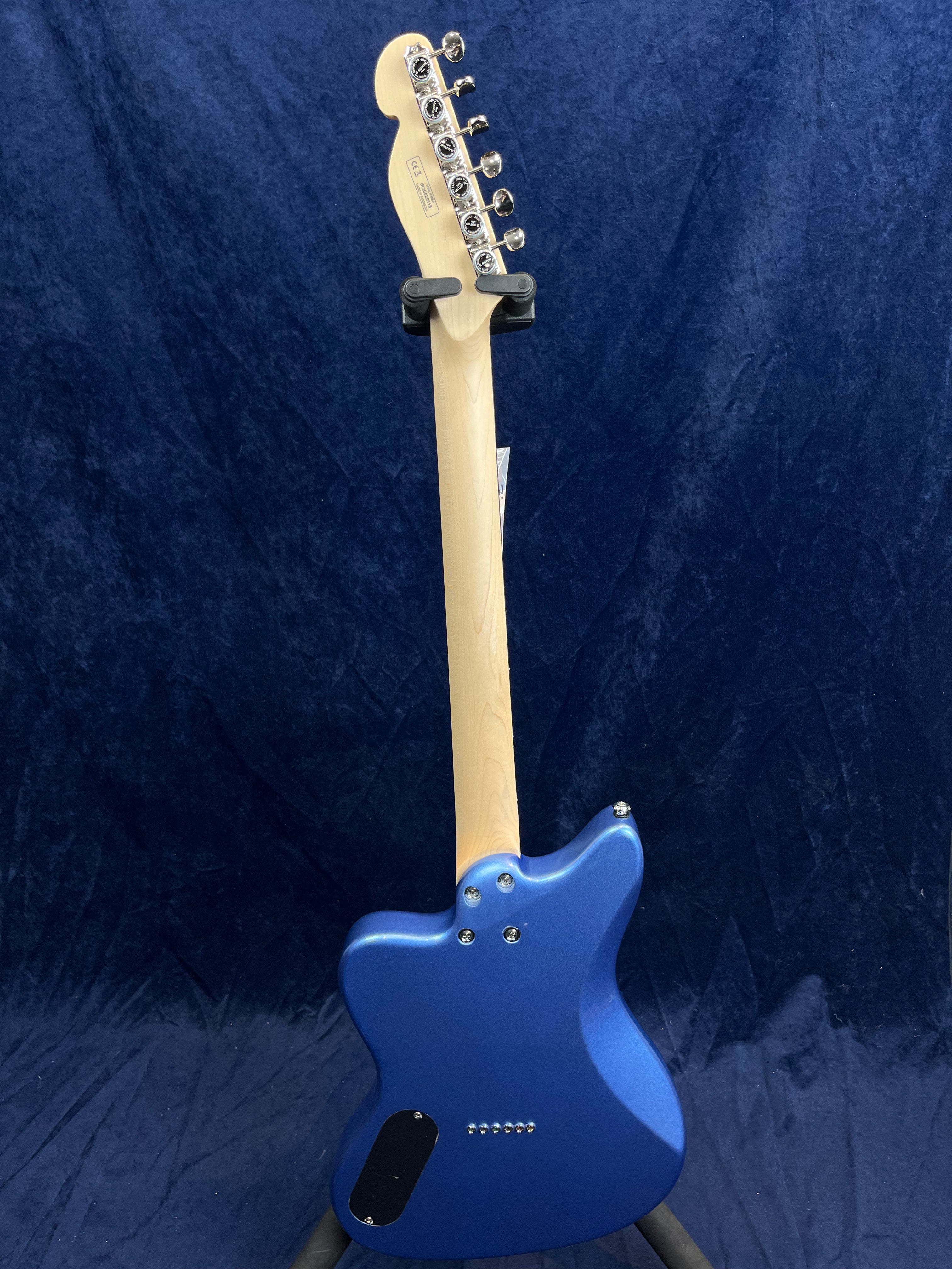 A blue electric guitar shown from the back, displaying a natural wood neck with six tuning pegs and visible bolts attaching the neck to the body.