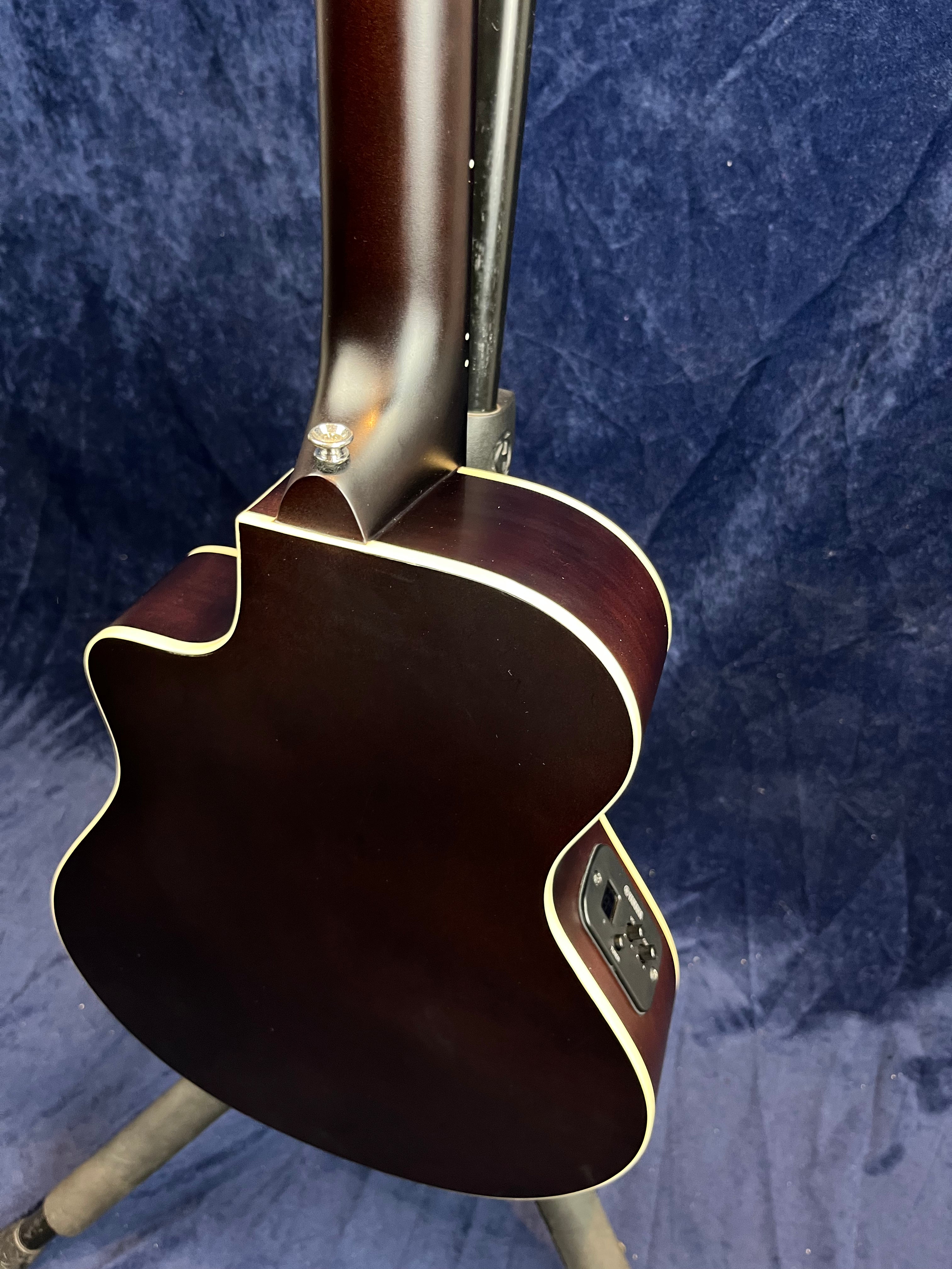 Dark brown acoustic guitar back and neck with cream binding, cutaway design, and onboard preamp controls visible on the side.