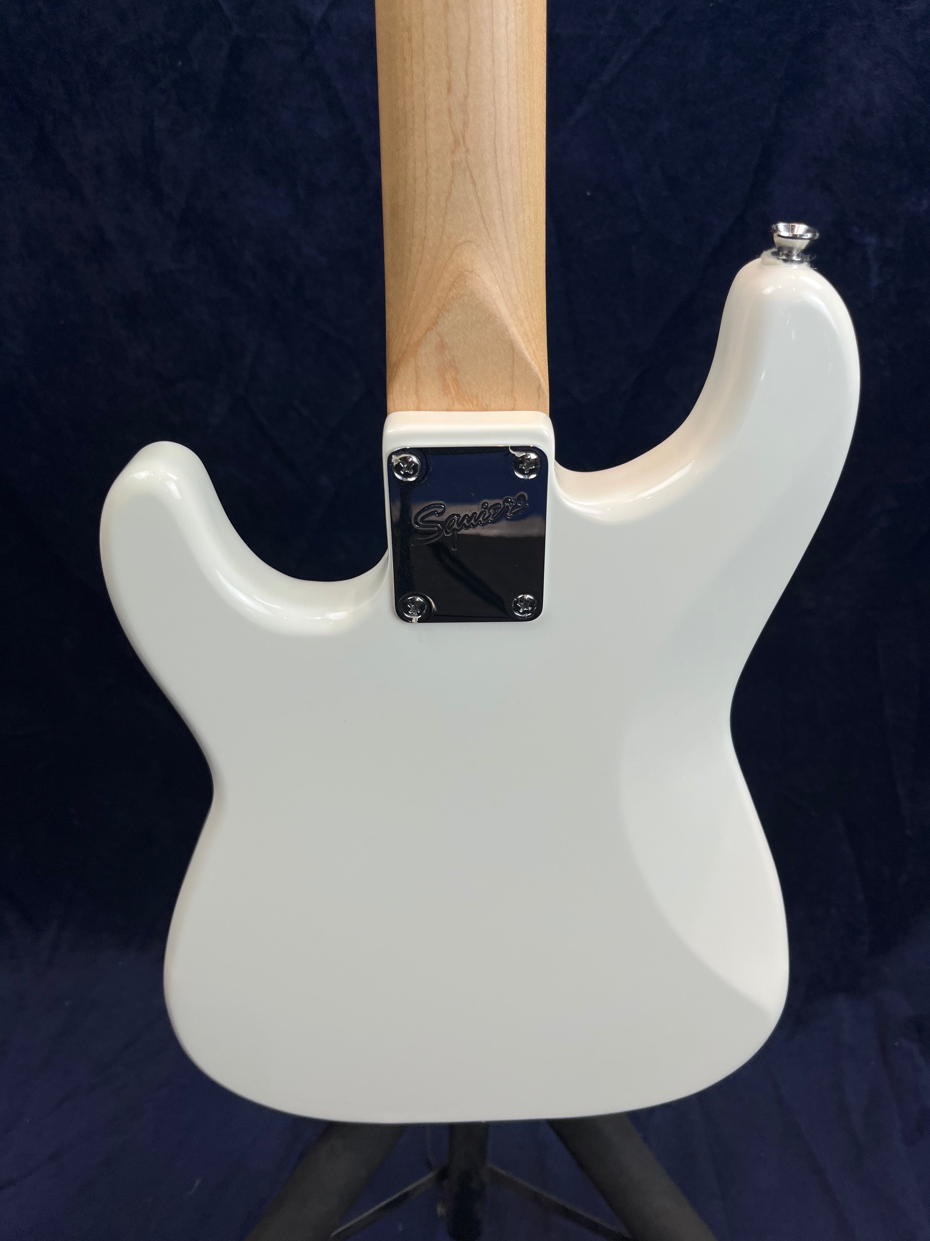 Back view of a white electric guitar body with a light wood neck, metal neck plate engraved with "Squier," and a single strap button visible.
