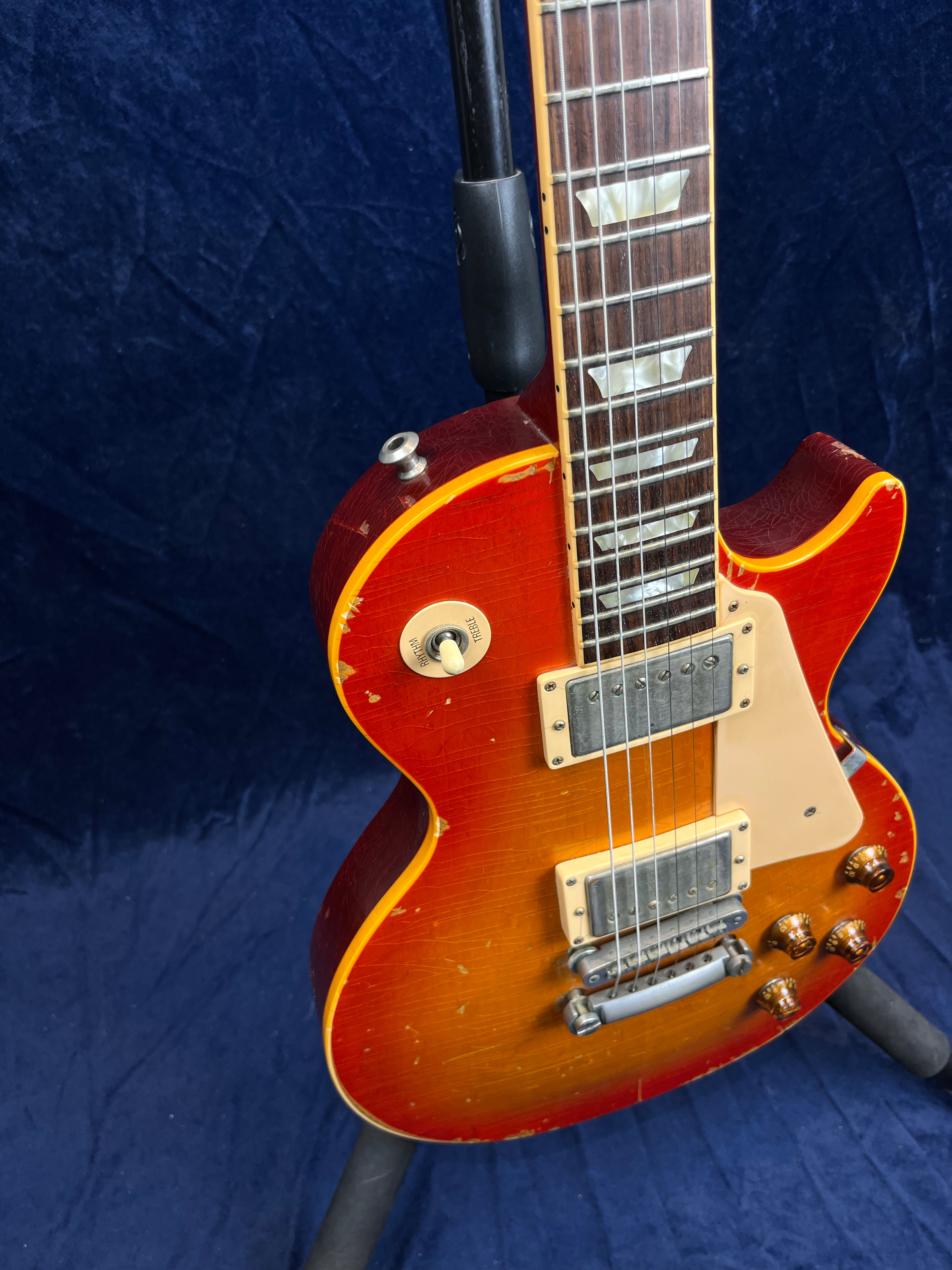 Sunburst electric guitar with a single cutaway, cream pickguard, two humbucker pickups, and visible scratches and wear on the body.