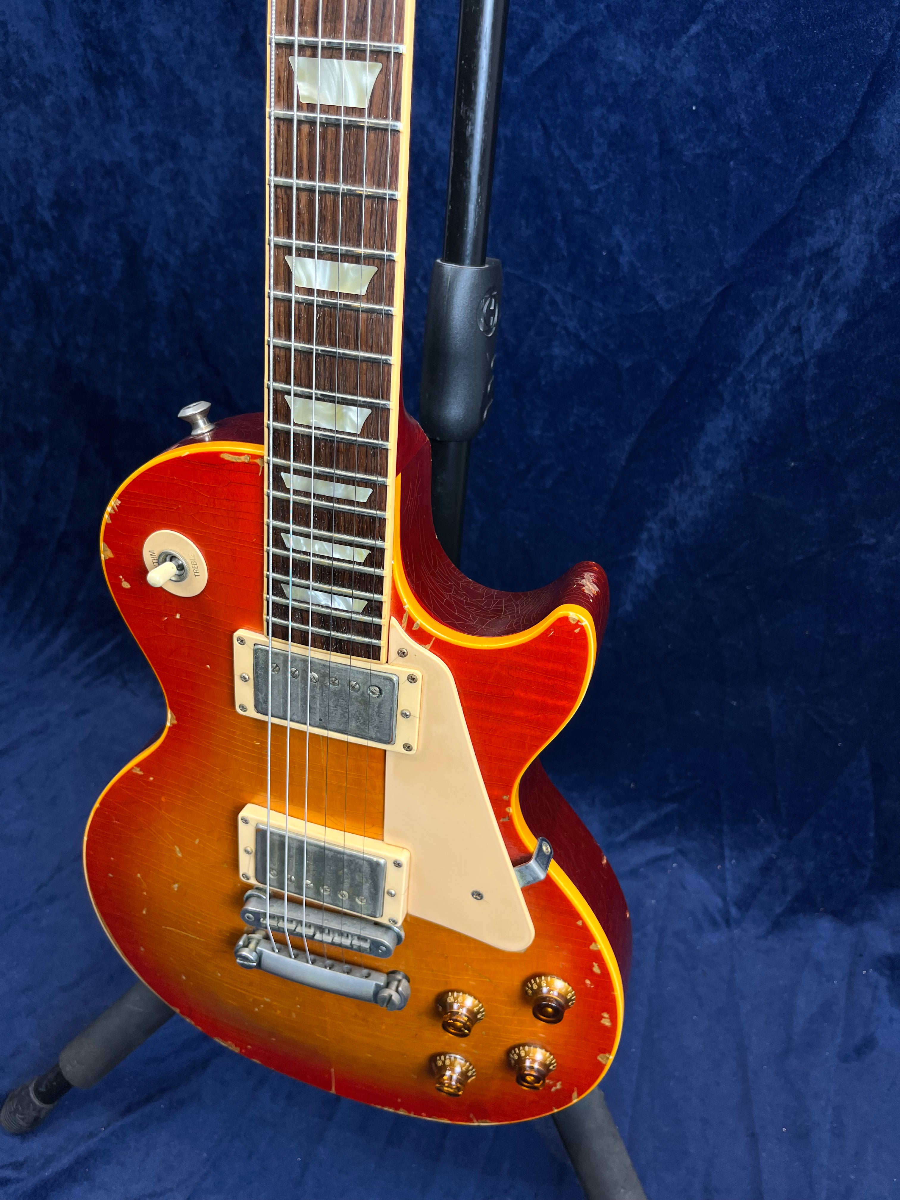 Sunburst electric guitar with a single cutaway, cream pickguard, four control knobs, two silver humbucker pickups, and visible signs of wear.