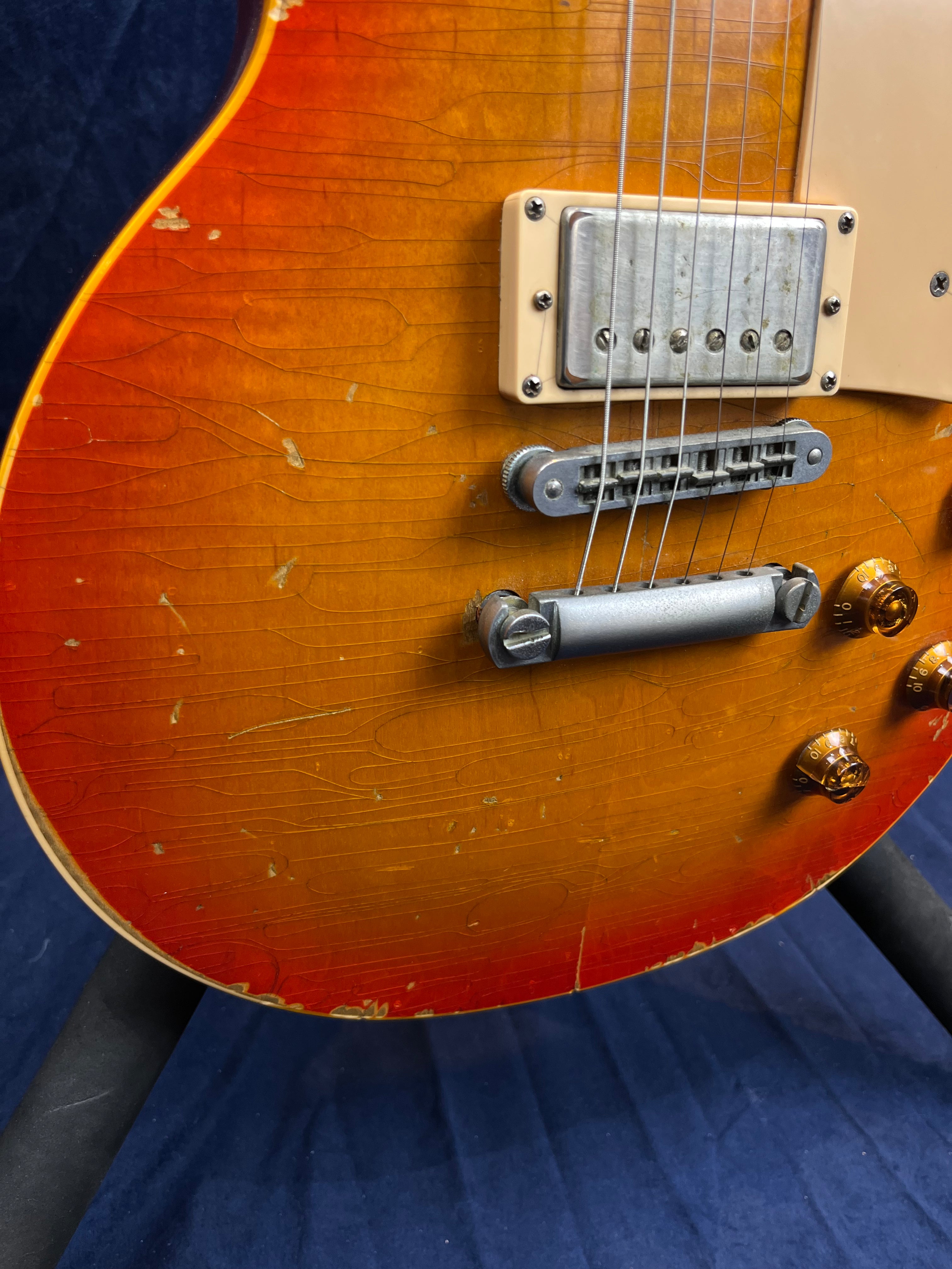 Sunburst electric guitar with visible scratches, dings, and finish checking near the bridge and pickup, showing signs of heavy use and age.