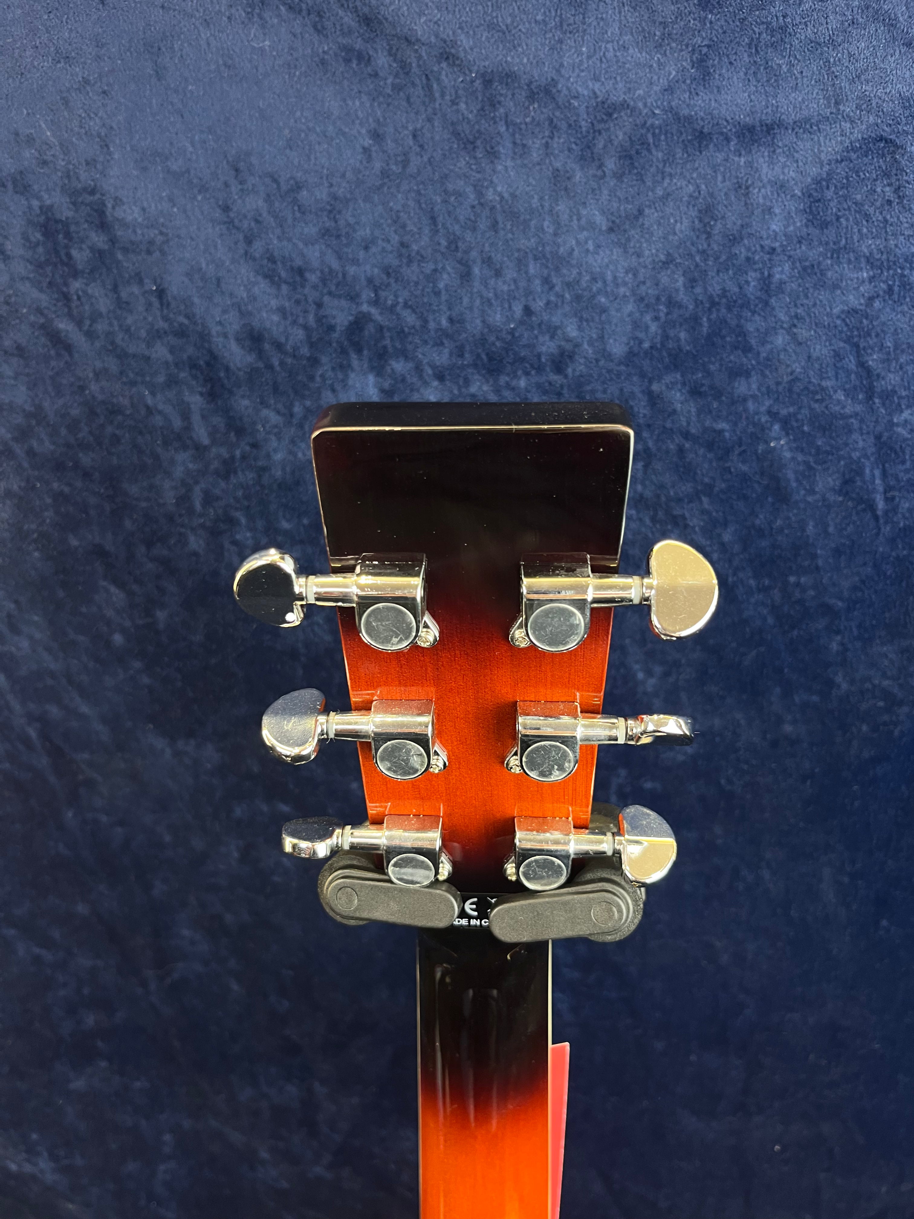 Back of a resonator guitar headstock with six chrome tuning pegs against a dark blue background.
