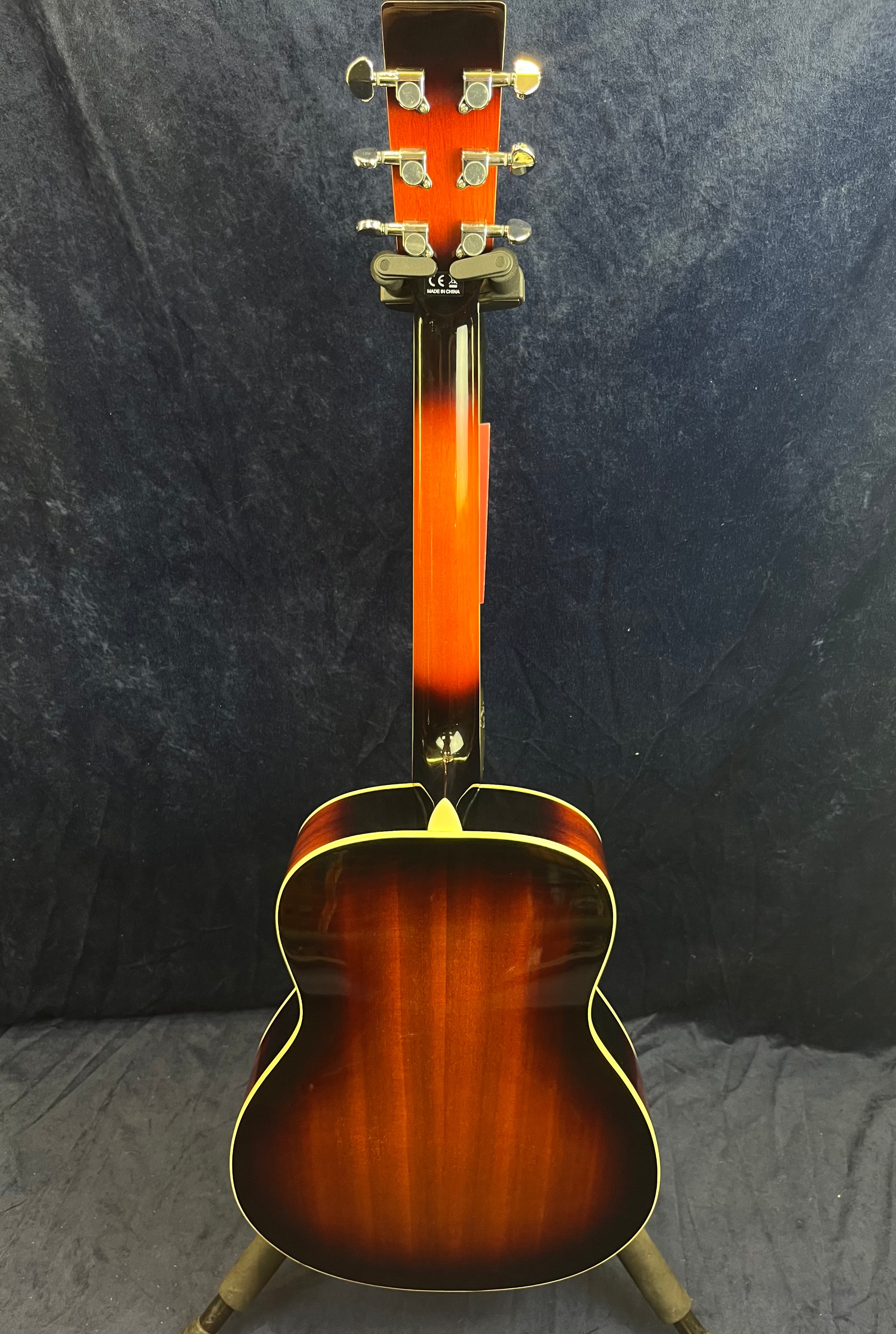 Resonator guitar viewed from the back, showing a glossy sunburst finish with cream binding, six tuning pegs, and a dark background.