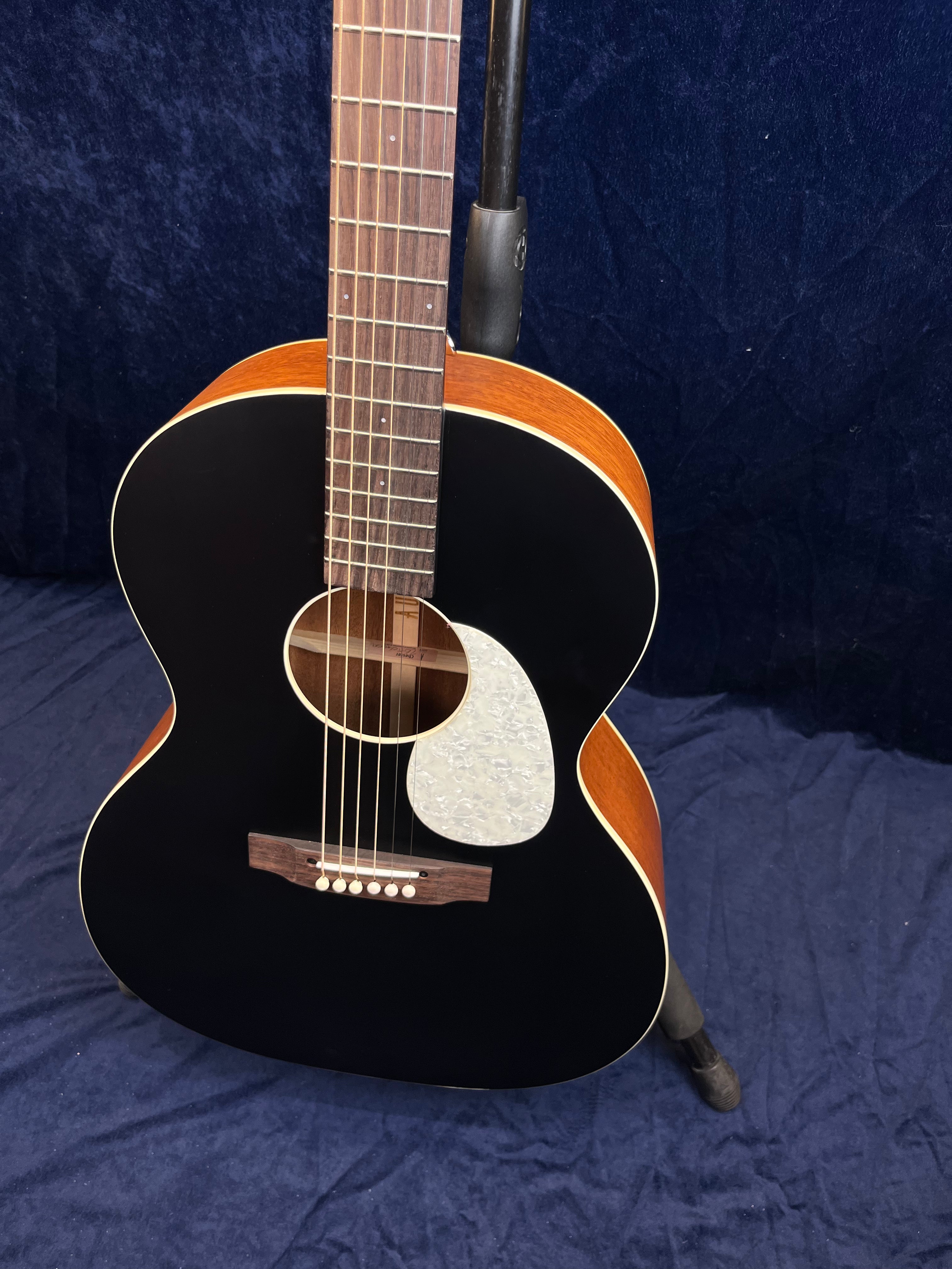 Guitare acoustique avec table noire, éclisses en bois clair et pickguard nacré blanc en forme de goutte sous la rosace.