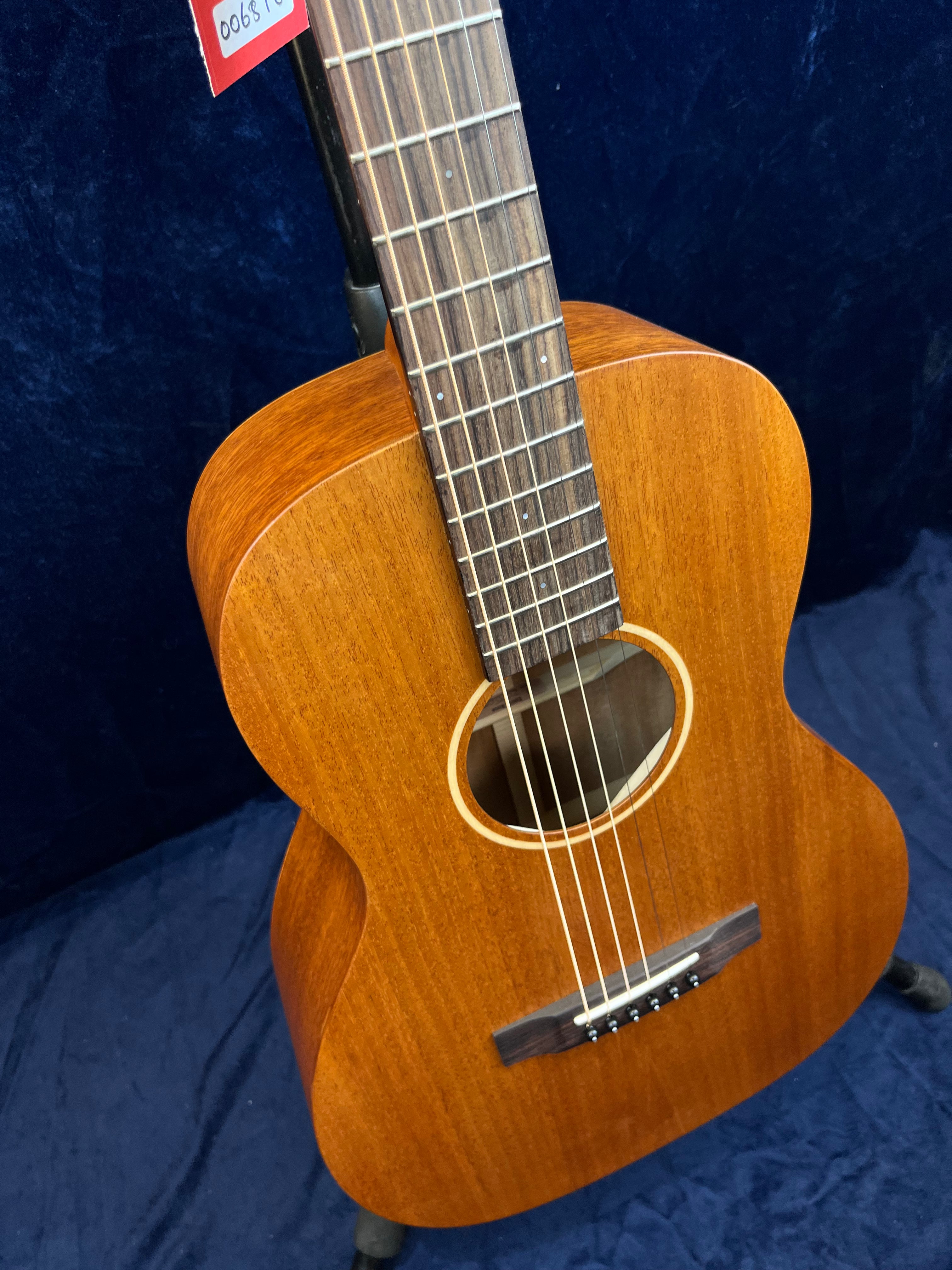 Small-bodied acoustic guitar with a natural wood finish, six strings, a simple round soundhole, and dot inlays on the fretboard.