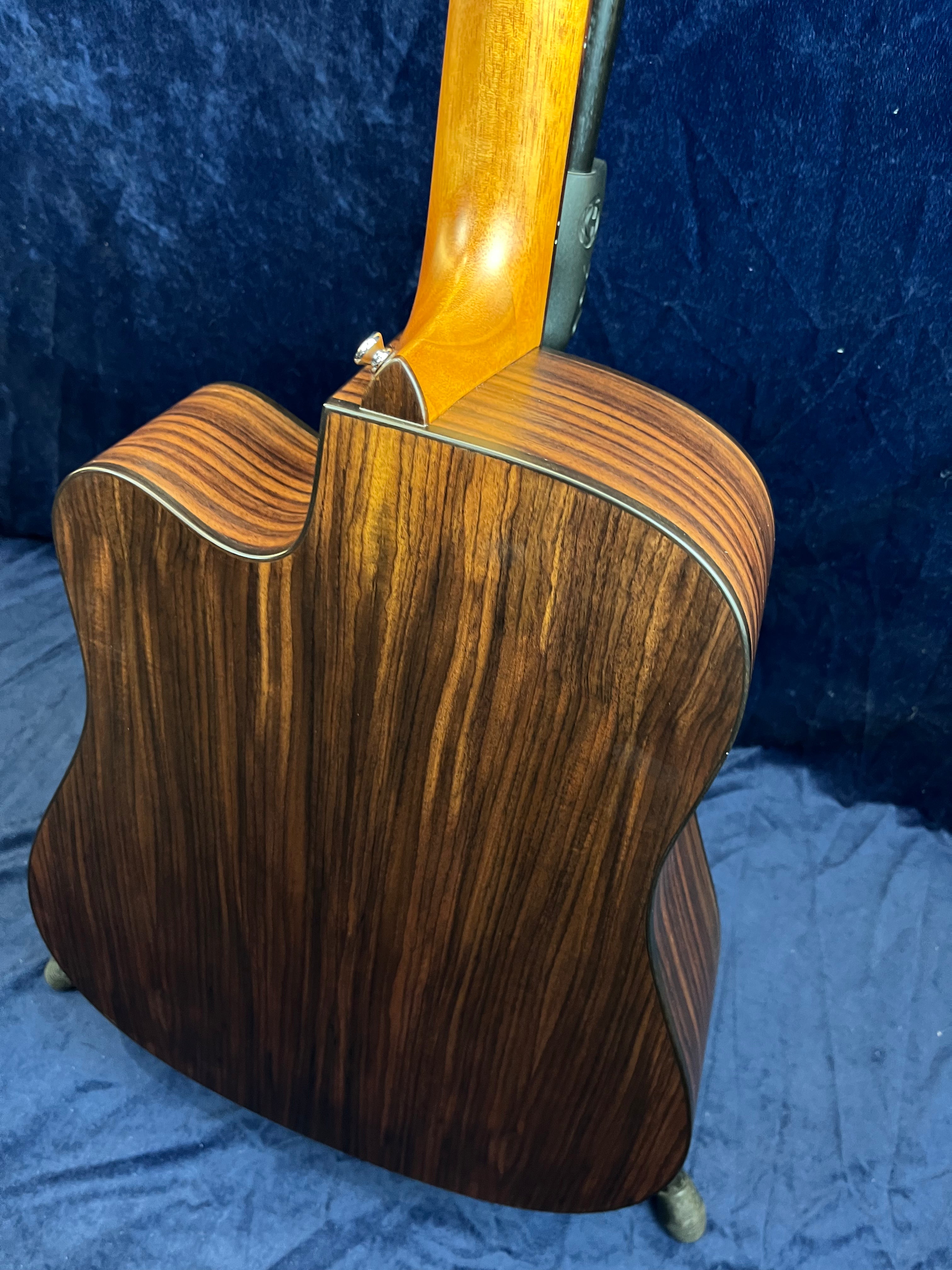 Guitare acoustique à pan coupé avec dos en bois veiné foncé et éclisses assorties, manche clair, finition brillante.
