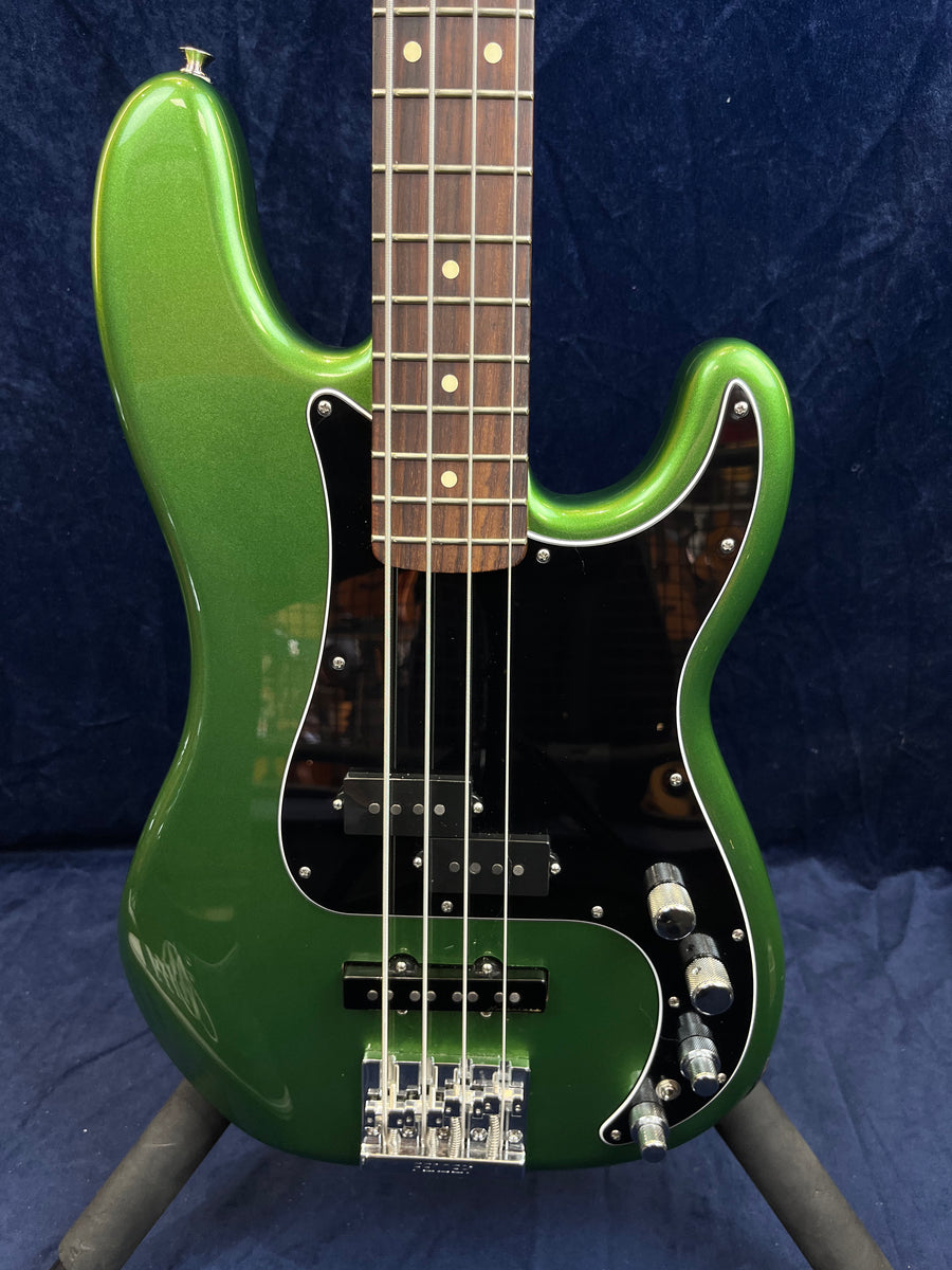 Metallic green four-string bass guitar with a black pickguard, silver bridge, control knobs, and a rosewood fretboard with dot inlays.