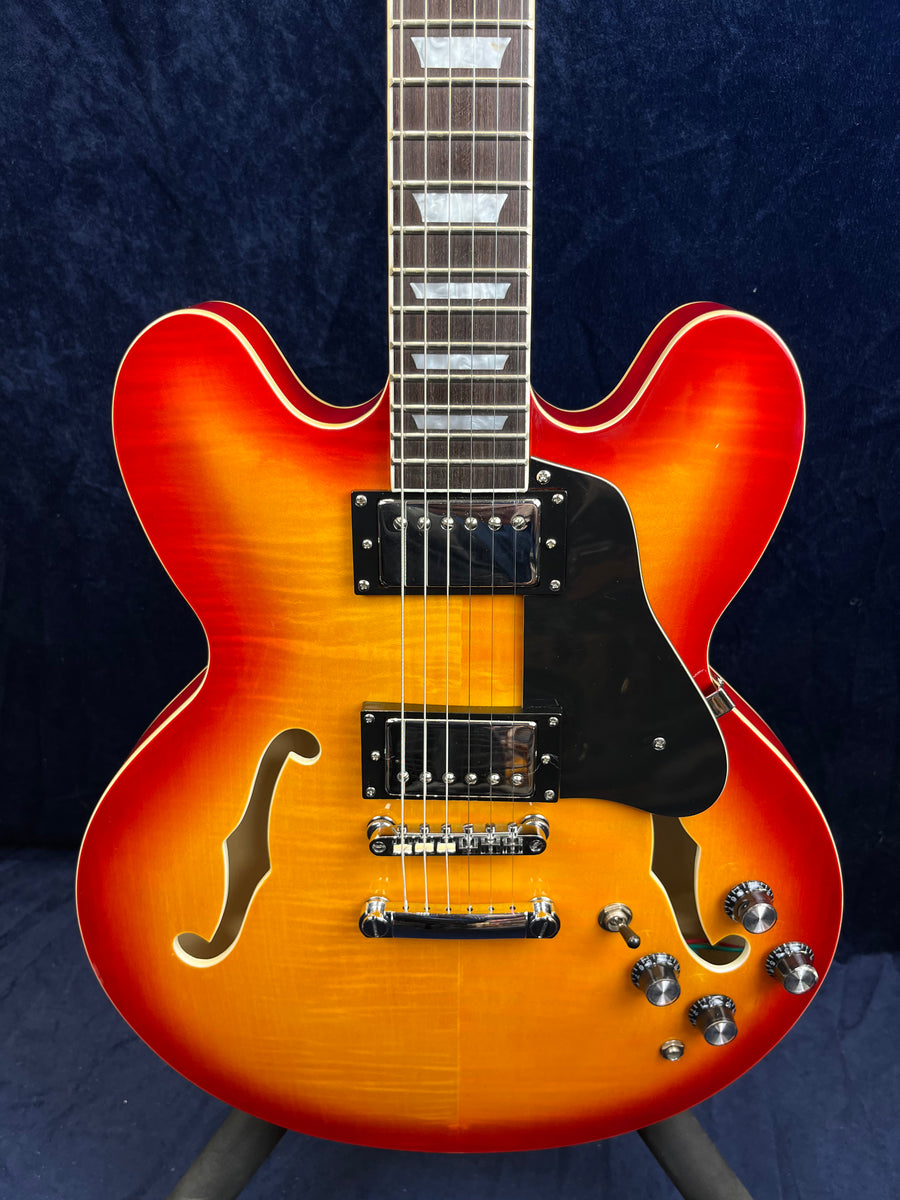 Sunburst semi-hollow electric guitar with double cutaways, two humbucker pickups, f-holes, black pickguard, and four control knobs.