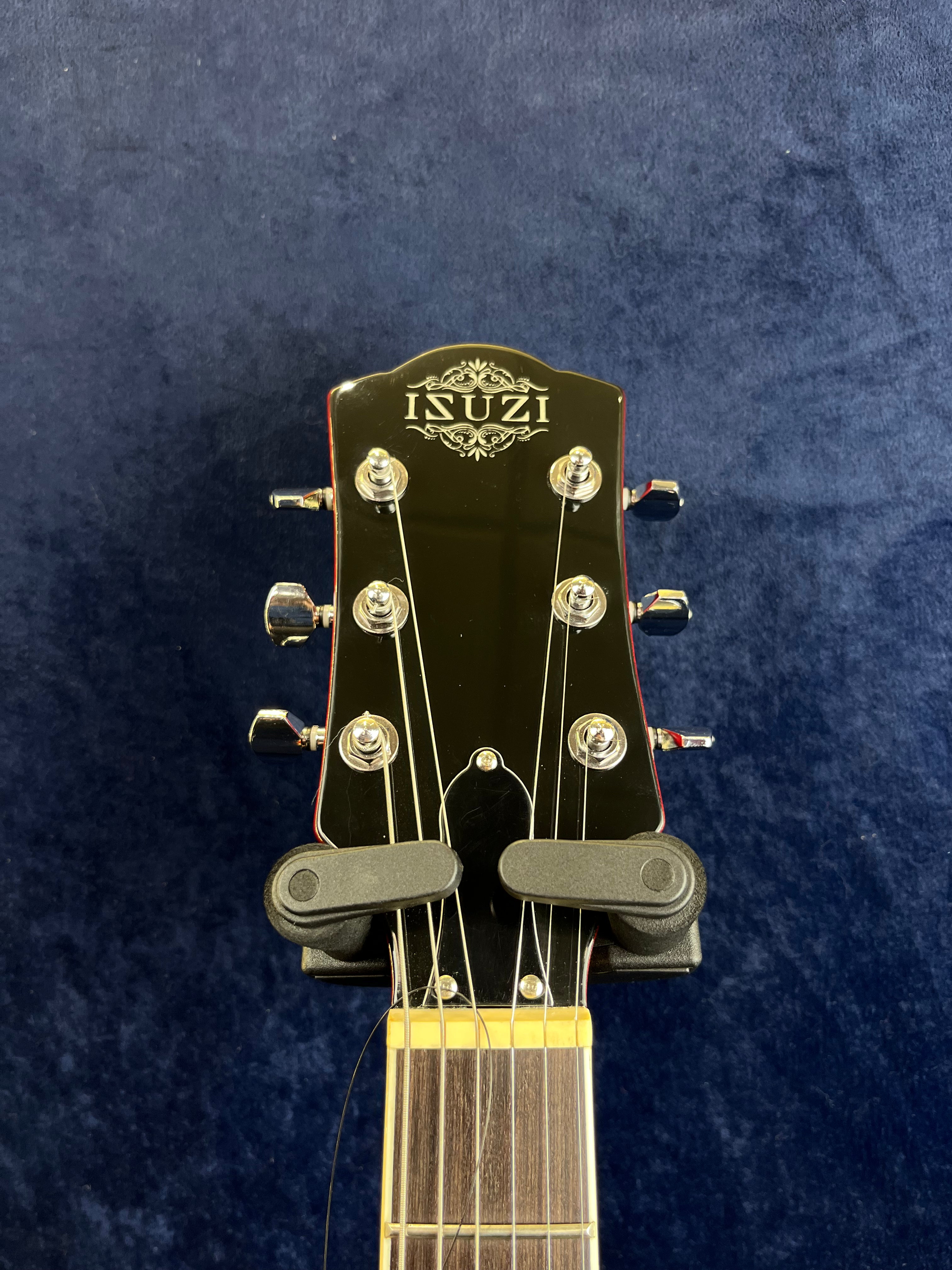 The headstock of an ISUZI electric guitar with six tuning pegs, string winders attached, and a decorative logo on a dark background.
