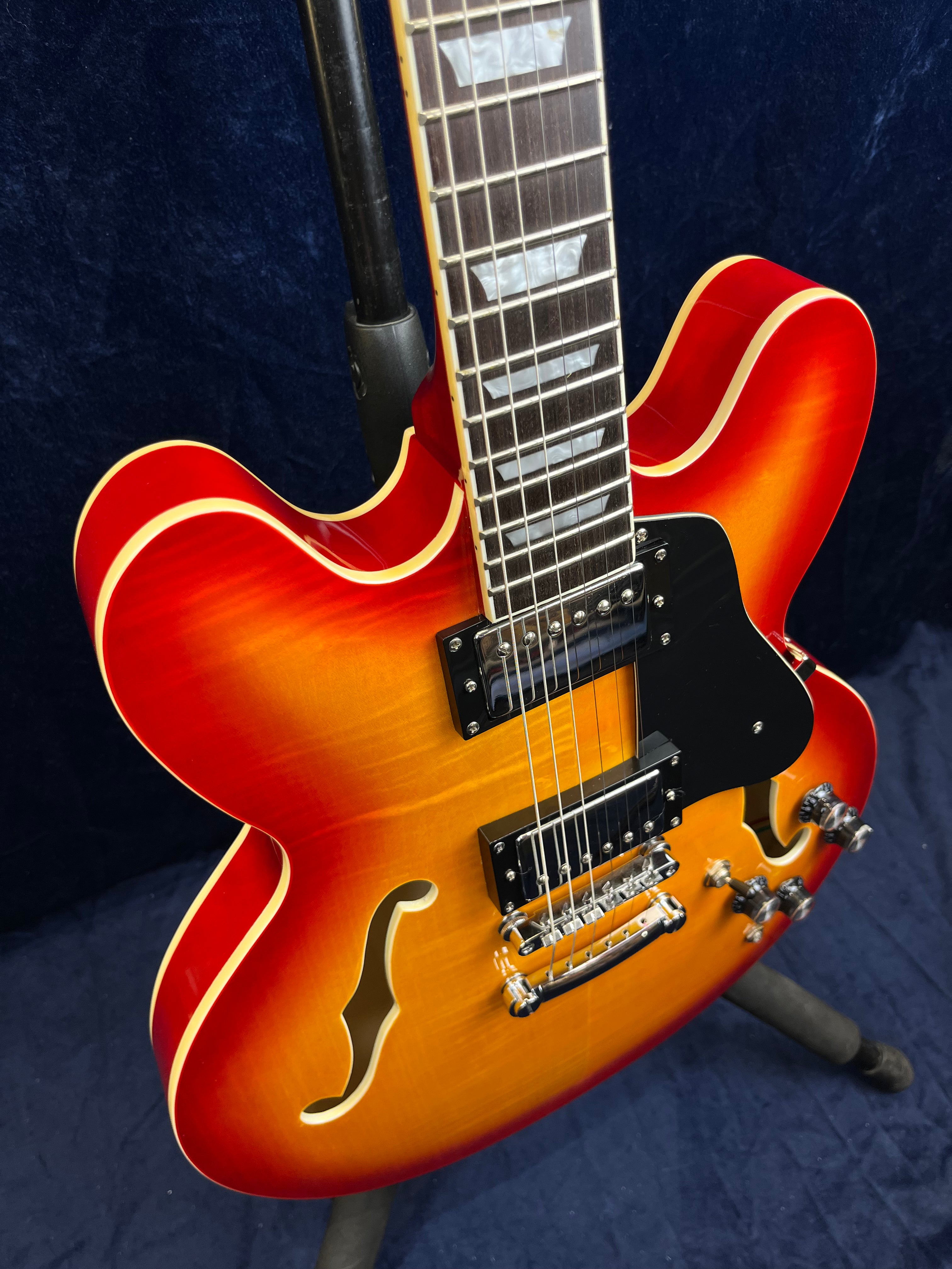 Semi-hollow electric guitar with a bright sunburst finish, dual humbucker pickups, four control knobs, f-holes, and a black pickguard.