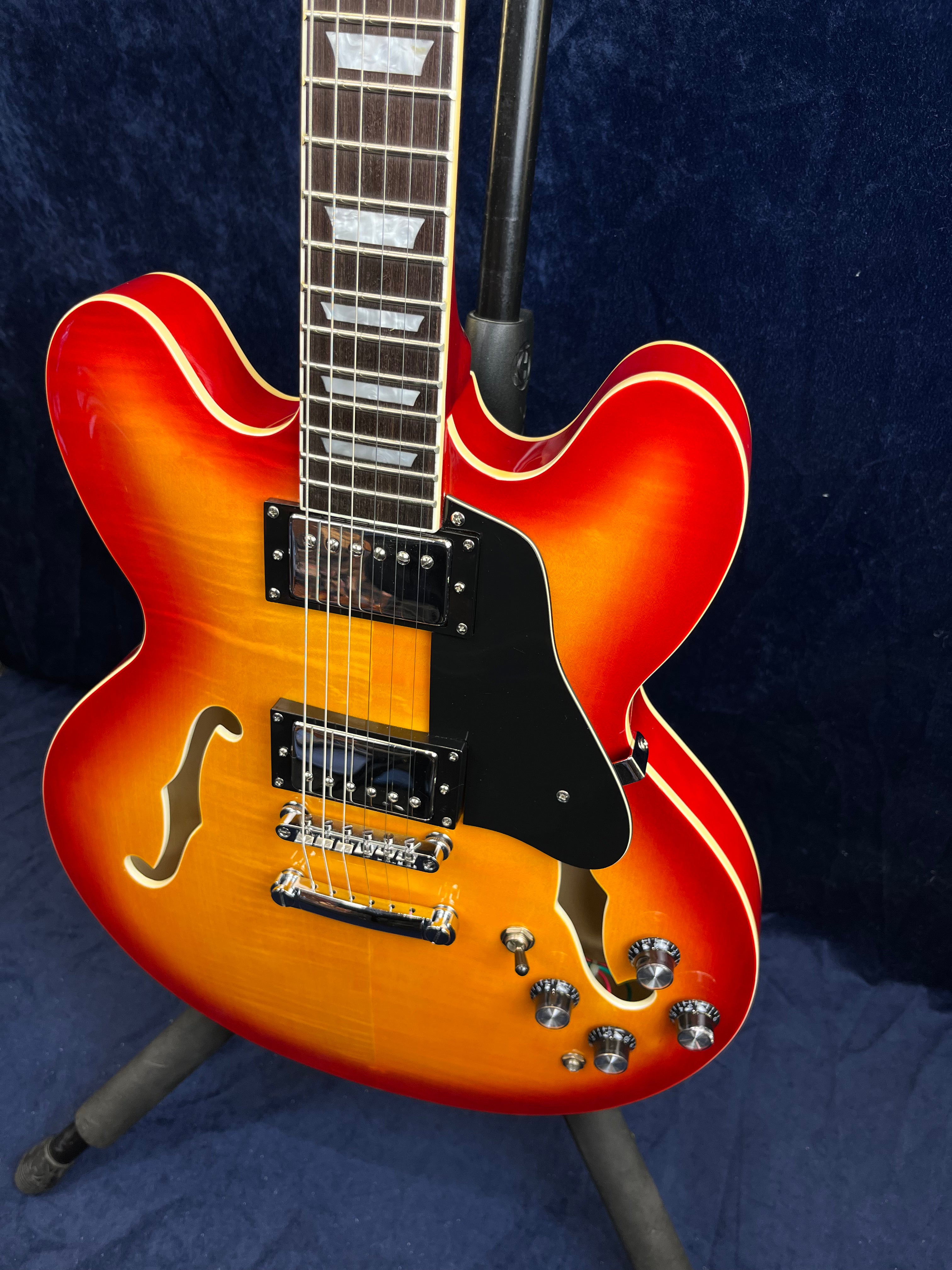 Sunburst semi-hollow electric guitar with two humbucker pickups, f-holes, chrome hardware, four control knobs, and a black pickguard.