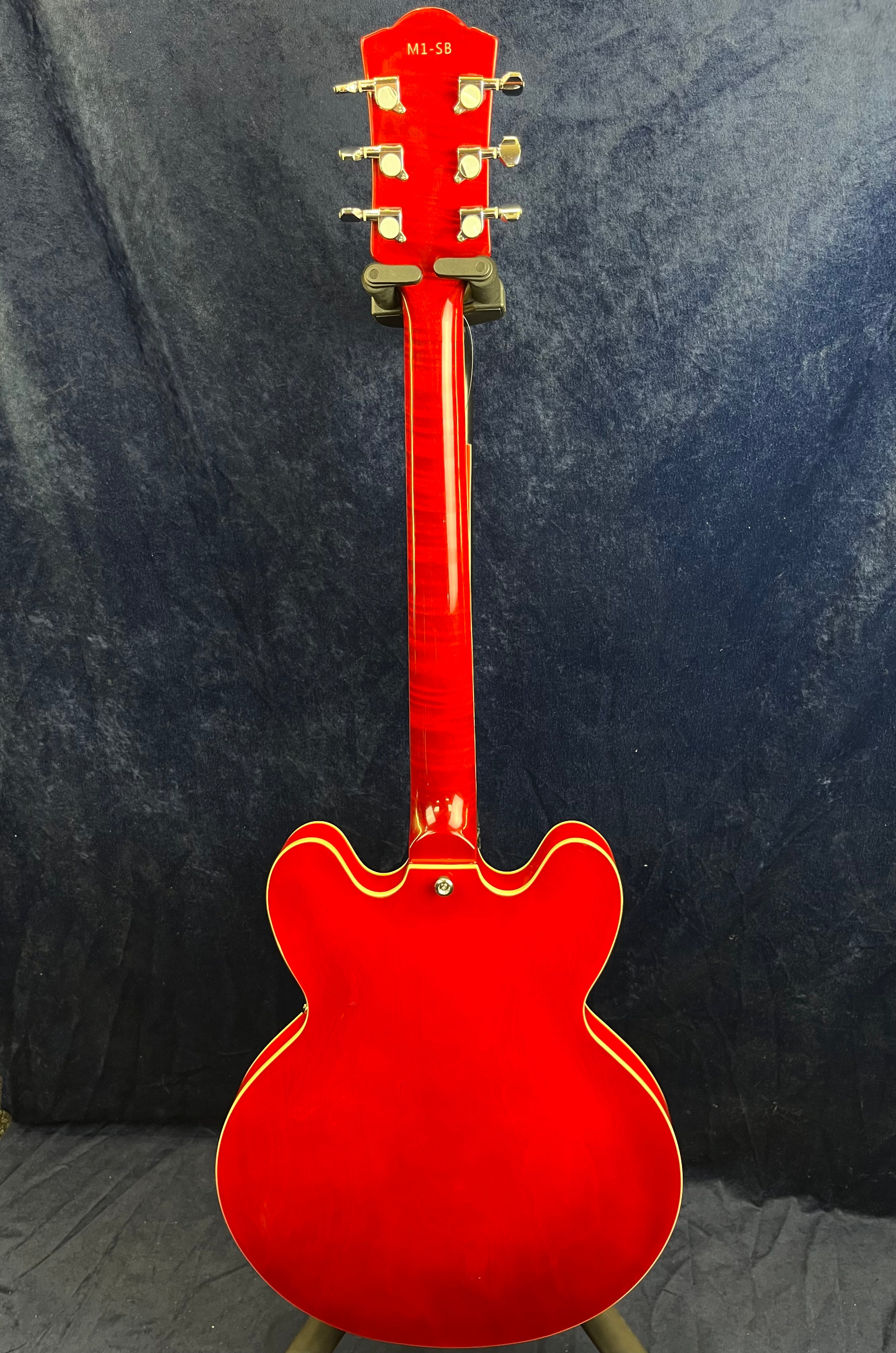 Bright red semi-hollow electric guitar shown from the back, featuring a double cutaway body and cream binding along the edges.