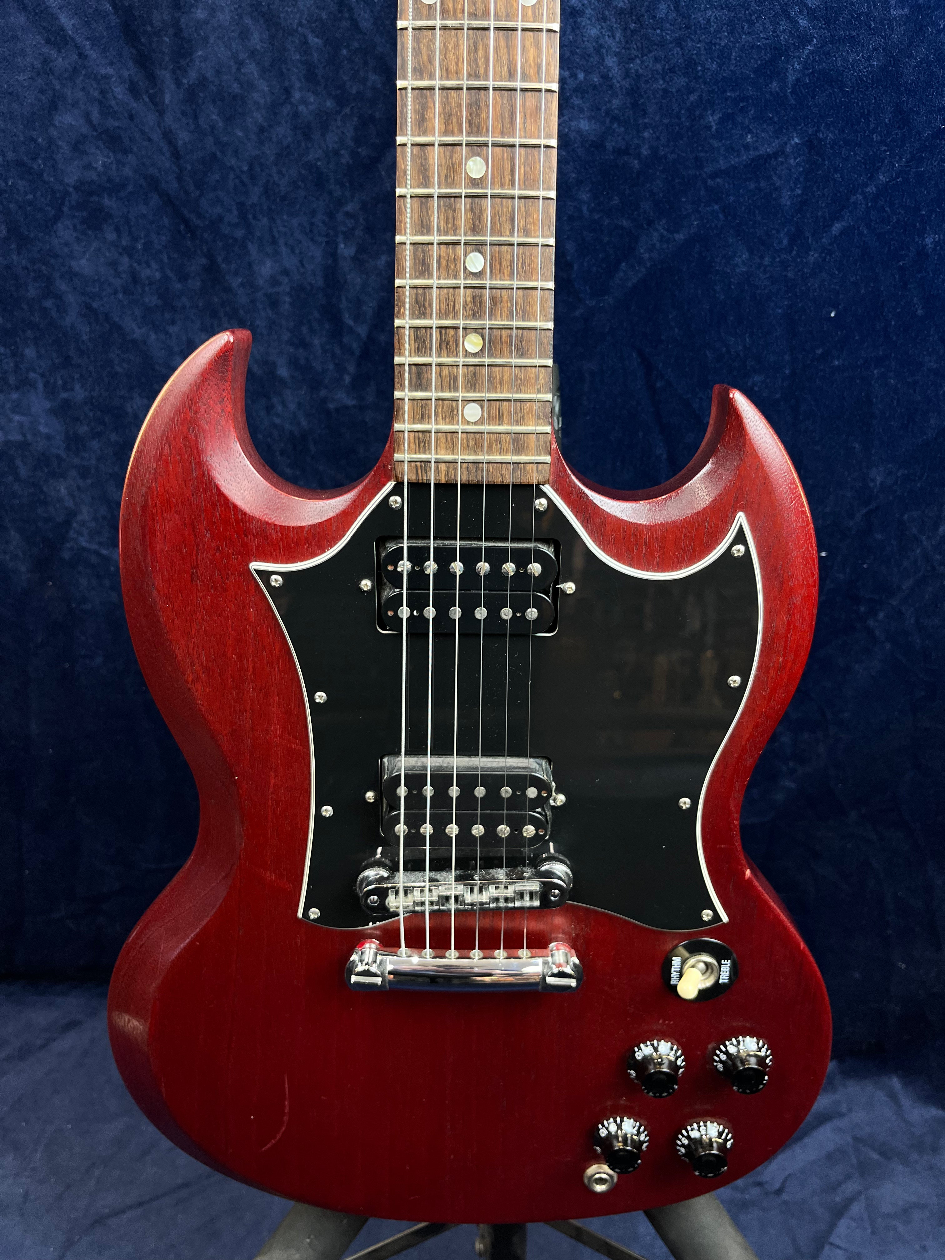 Cherry red electric guitar with a double-cutaway body, black pickguard, two humbucker pickups, four black control knobs, and a toggle switch.