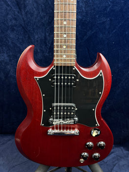 Cherry red electric guitar with a double-cutaway body, black pickguard, two humbucker pickups, four black control knobs, and a toggle switch.