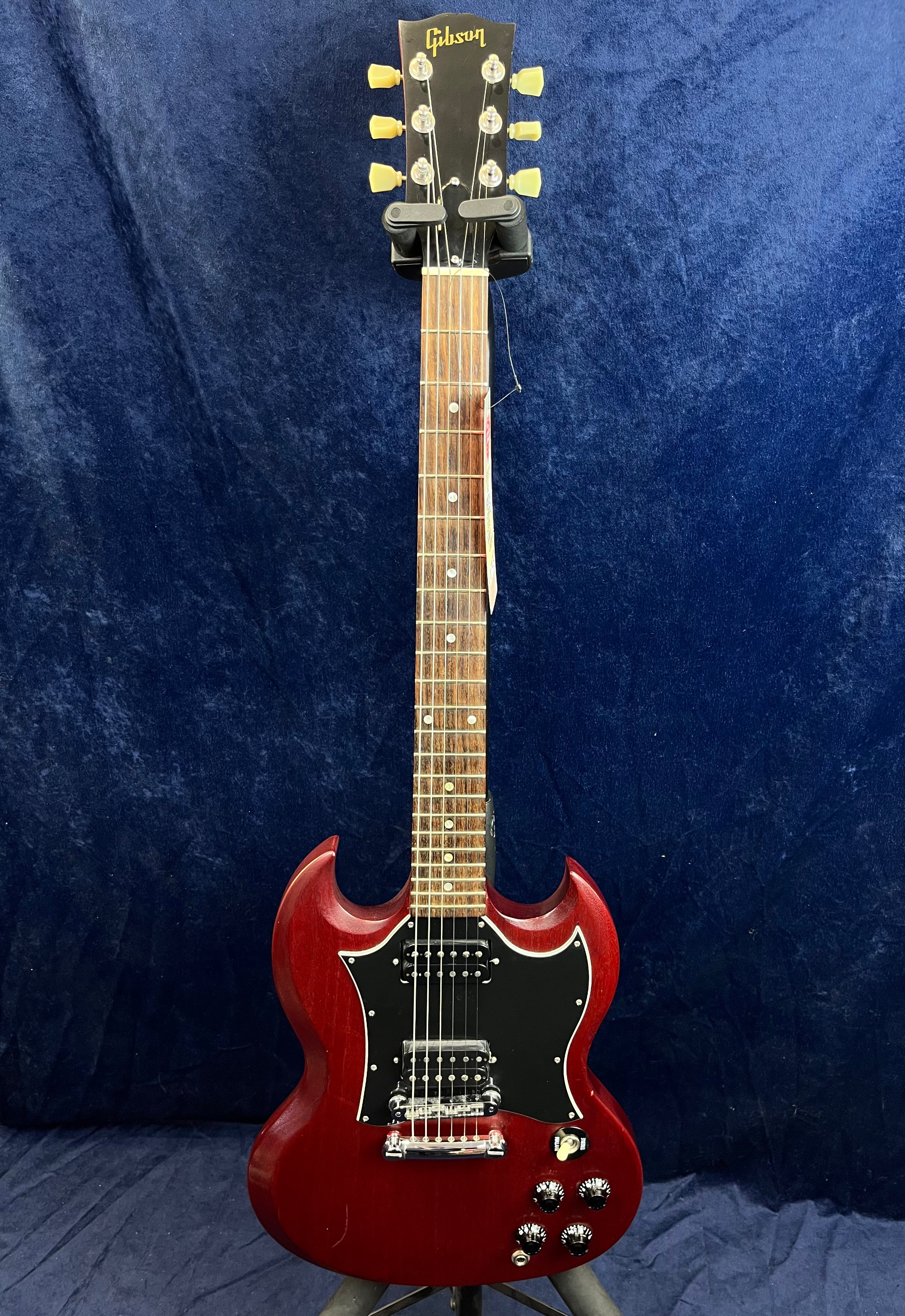 Red Gibson electric guitar with a double-cutaway body, black pickguard, two humbucker pickups, four control knobs, and a rosewood fretboard.