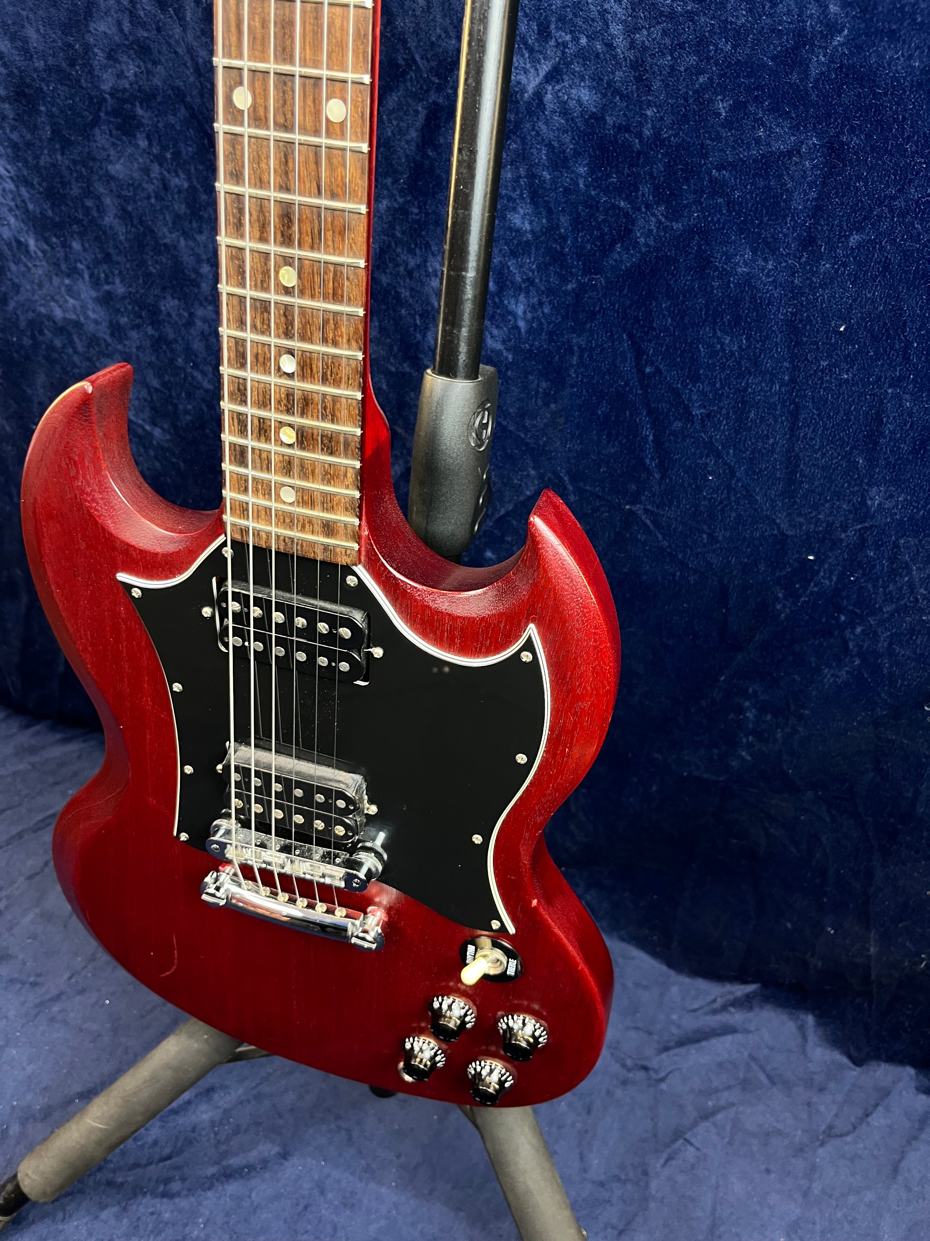 Cherry red electric guitar with a double-cutaway design, black pickguard, chrome hardware, four control knobs, and a toggle switch.