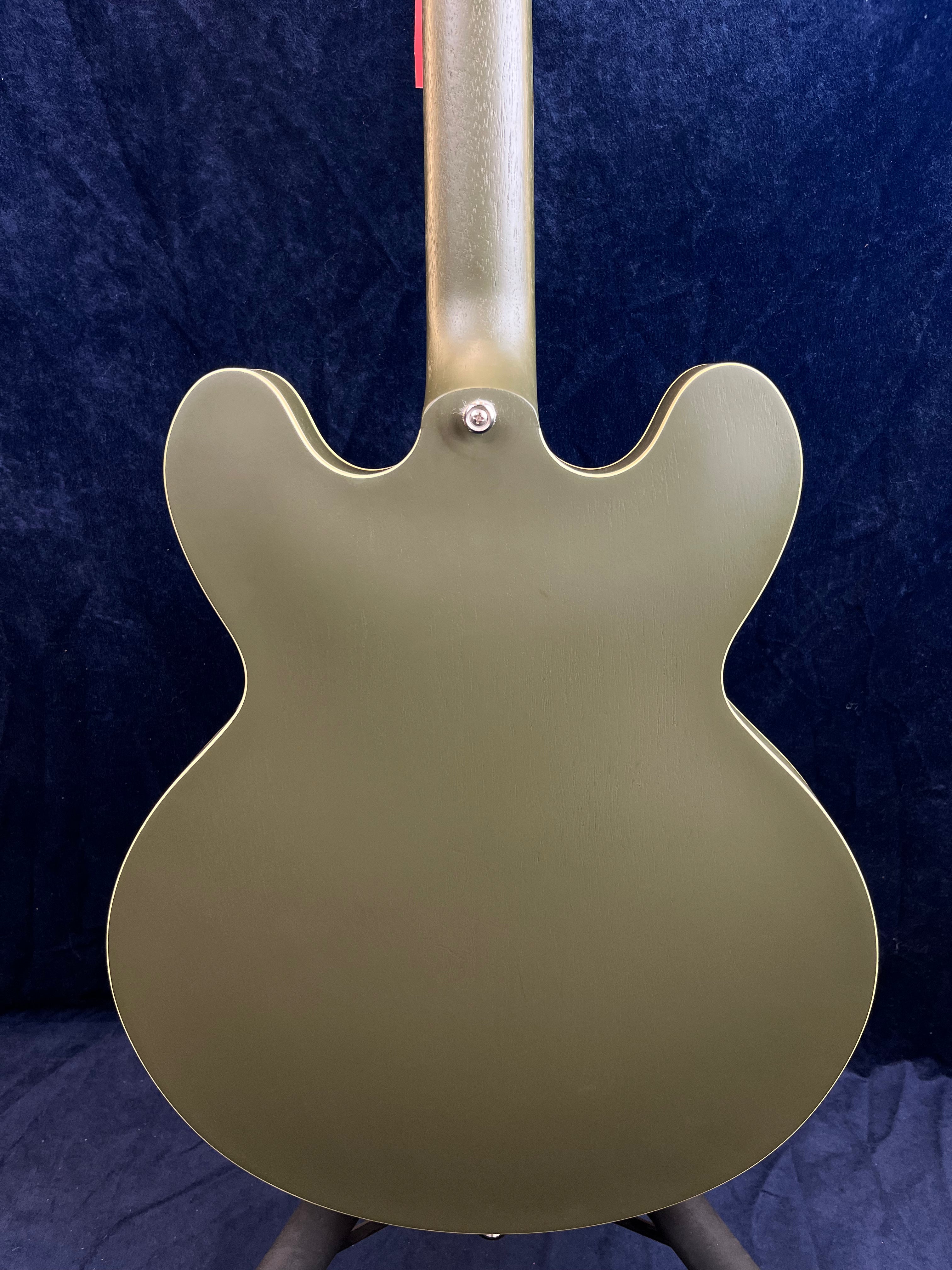 Olive green semi-hollow electric guitar shown from the back, with a smooth, matte finish and double cutaway body shape.