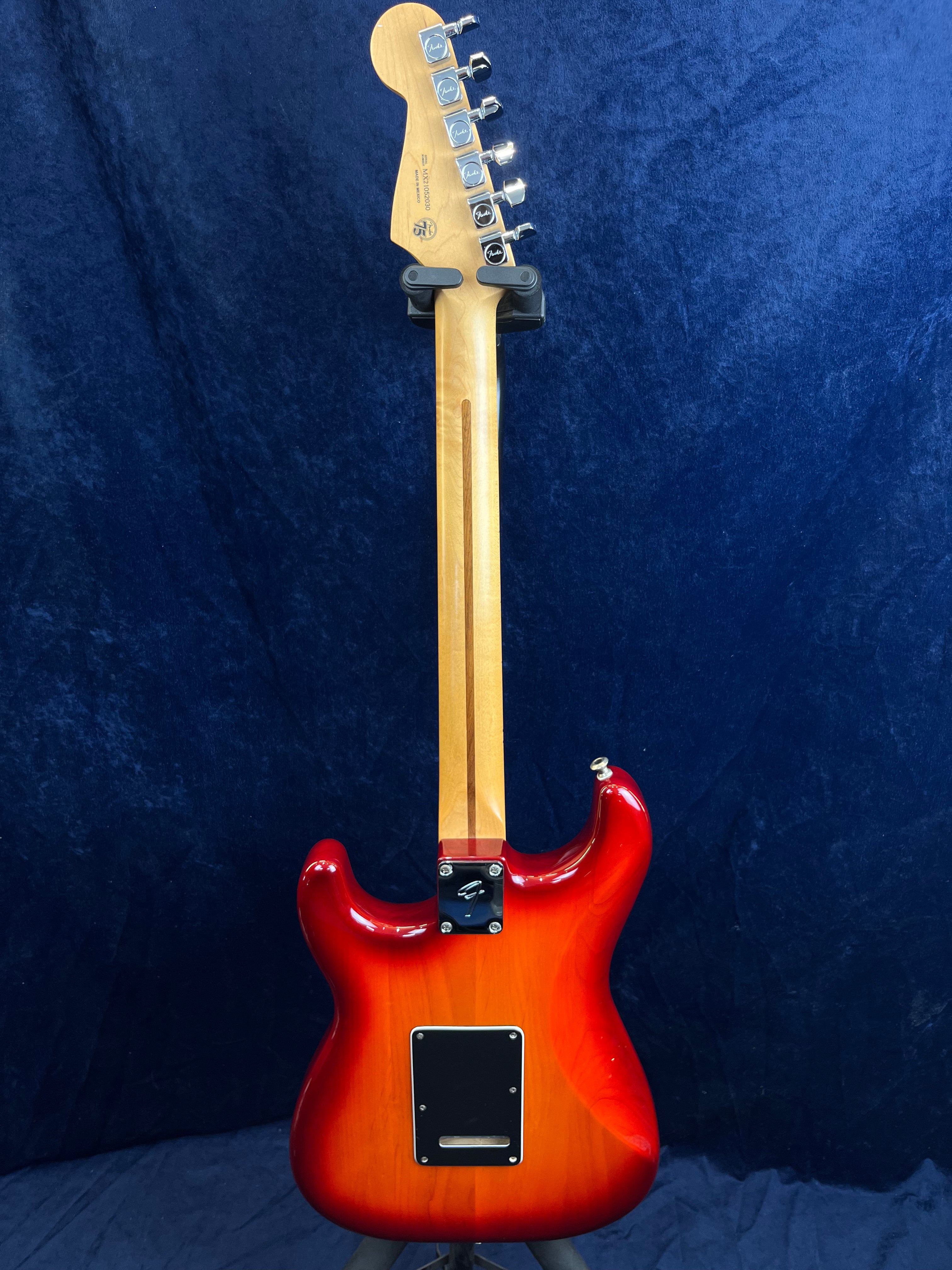 Guitare électrique vue de dos, corps rouge dégradé vers orange, manche en bois clair, plaques noires à l’arrière pour l’électronique et la tige vibrato.