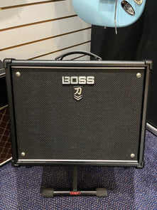Black Boss guitar amplifier with a textured front panel, silver Boss logo, carry handle on top, and sitting on a Dixon stand.