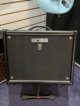 Black Boss guitar amplifier with a textured front panel, silver Boss logo, carry handle on top, and sitting on a Dixon stand.