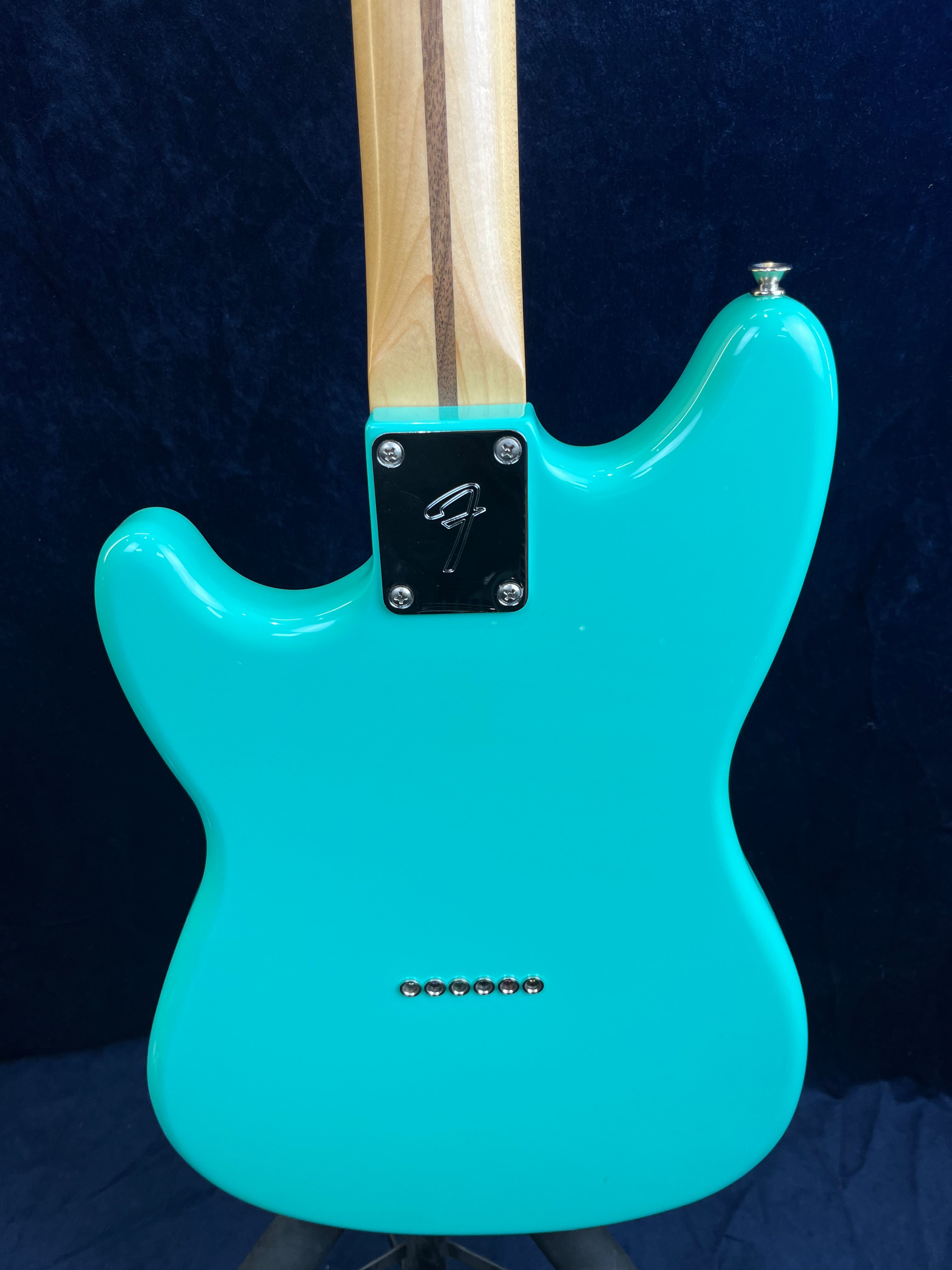 Aqua blue electric guitar back, maple neck with dark stripe, six metal string ferrules, and a silver neck plate engraved with an F.