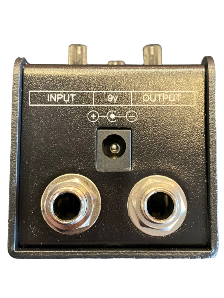 Black FX pedal face with labeled input and output jacks, plus a 9V power input between them. All connections are on one panel.