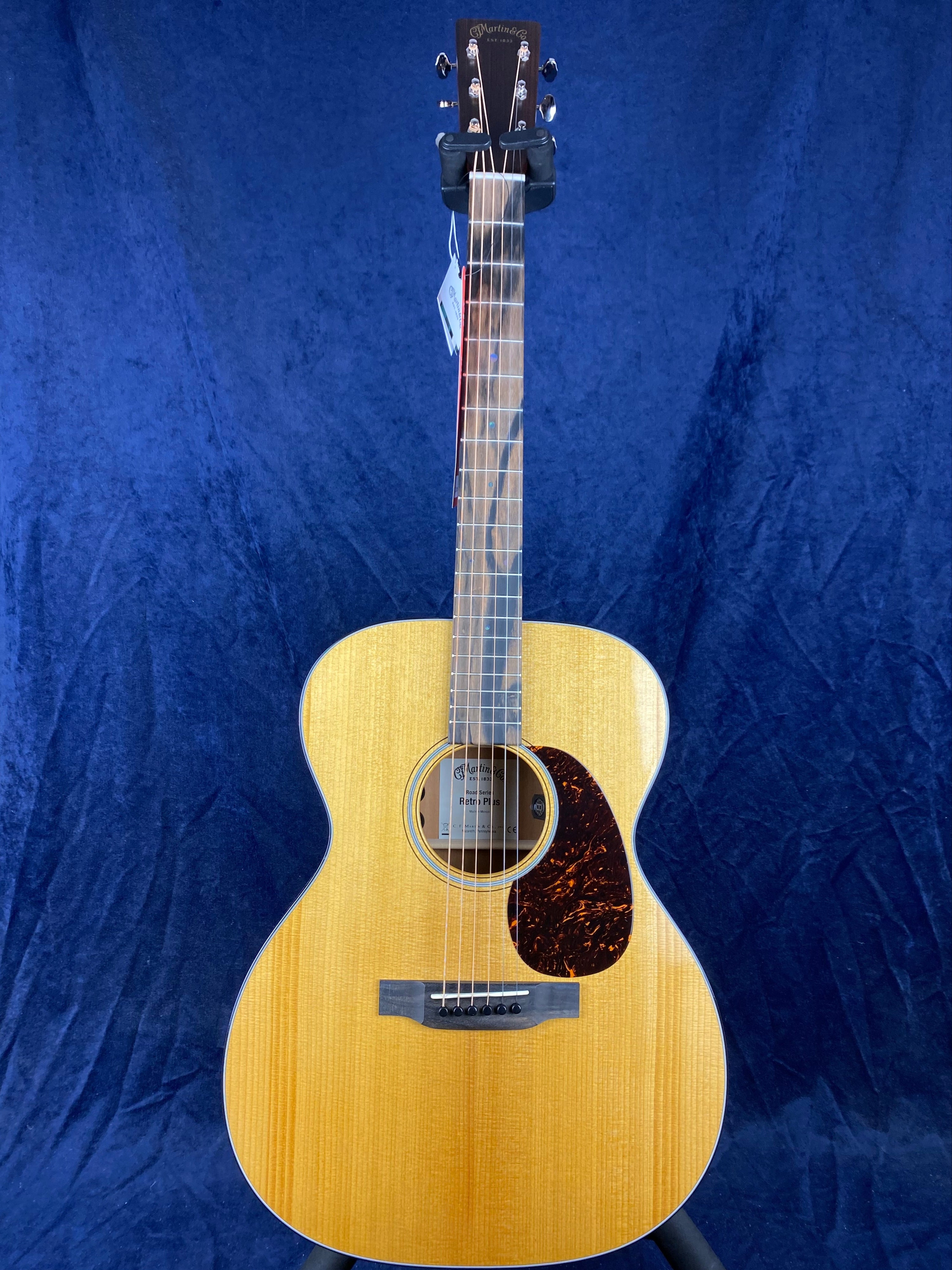 Light wood acoustic guitar with a round body, dark tortoiseshell pickguard, six strings, and a Martin & Co. logo on the headstock.