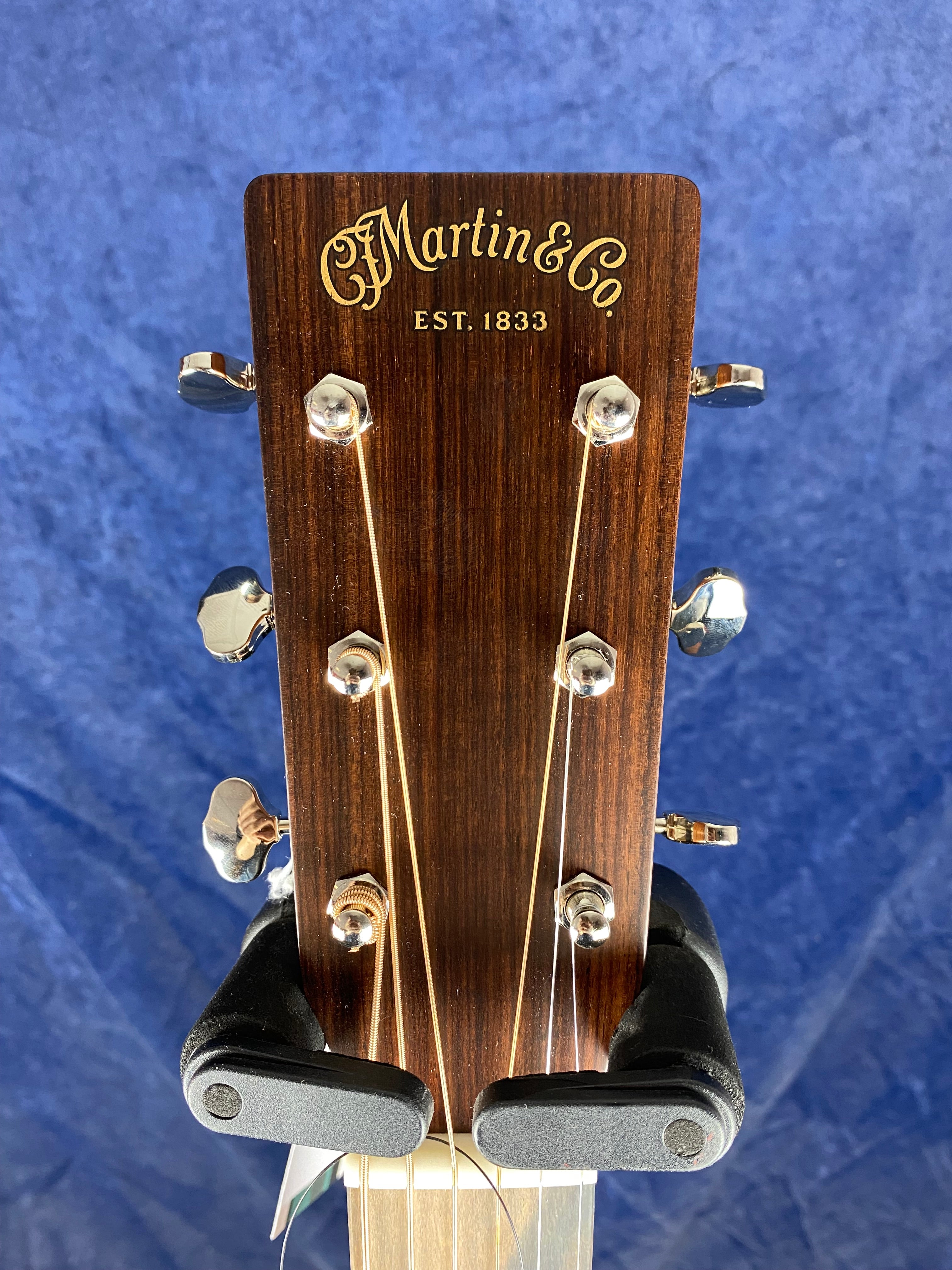 Close-up of a Martin & Co. acoustic guitar headstock with six tuning pegs and gold lettering on dark wood.
