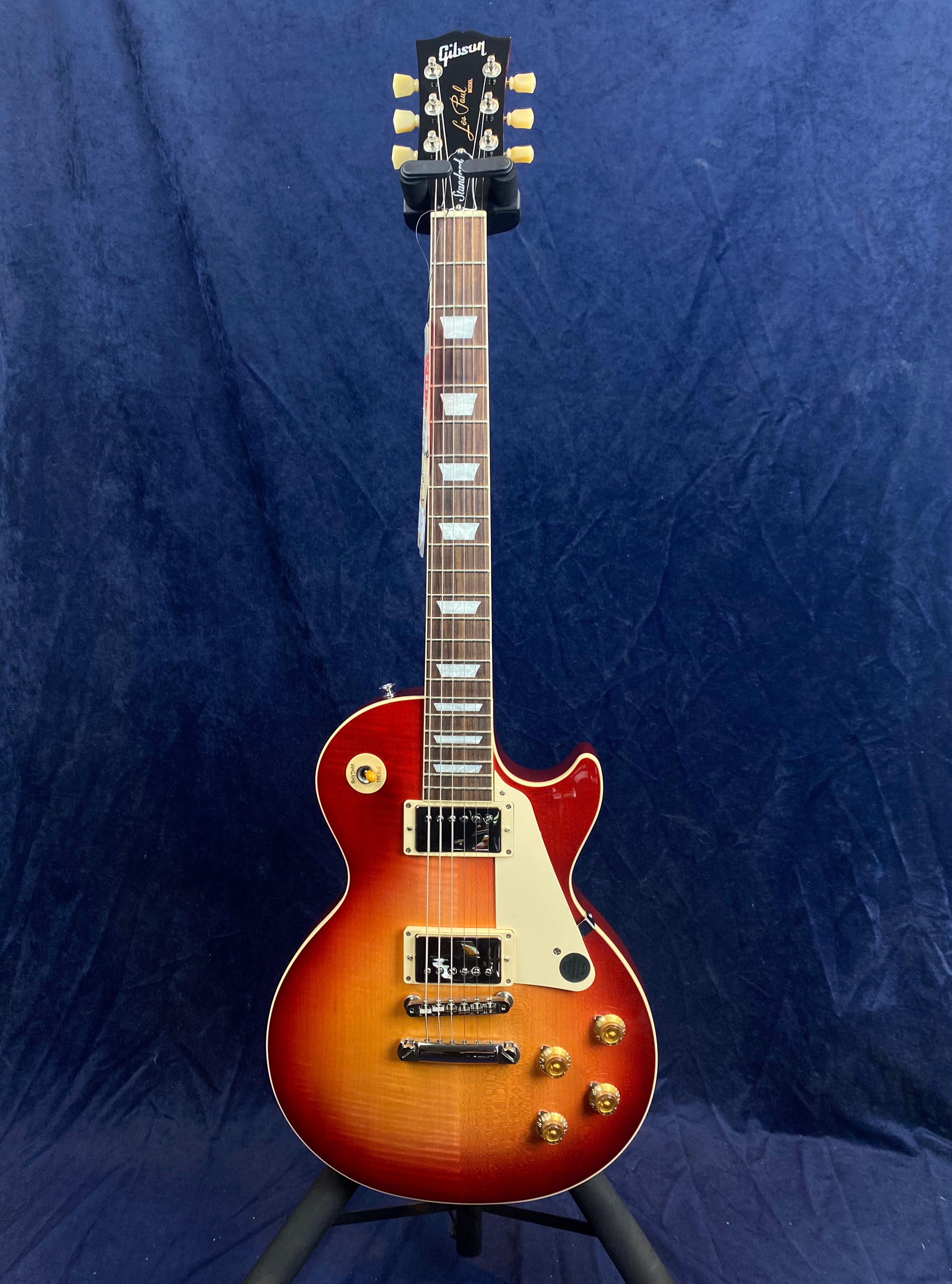 Gibson Les Paul electric guitar with a sunburst finish, white pickguard, gold control knobs, and rectangular inlays on a rosewood fretboard.