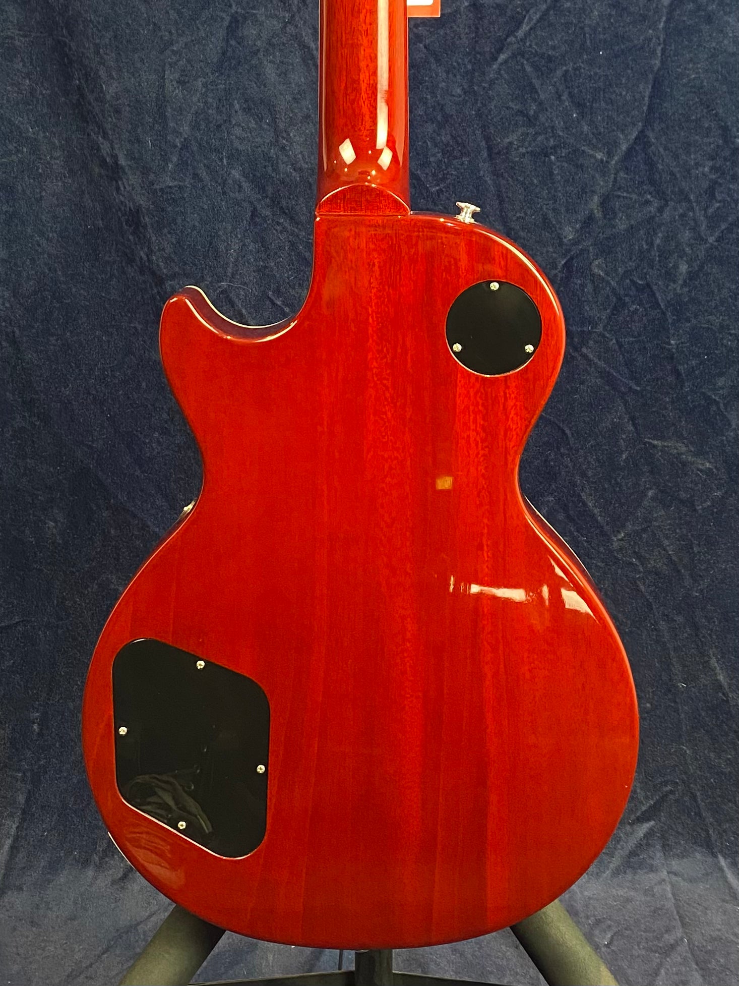 Red electric guitar shown from the back, with two black control cavity covers and a glossy finish against a dark background.