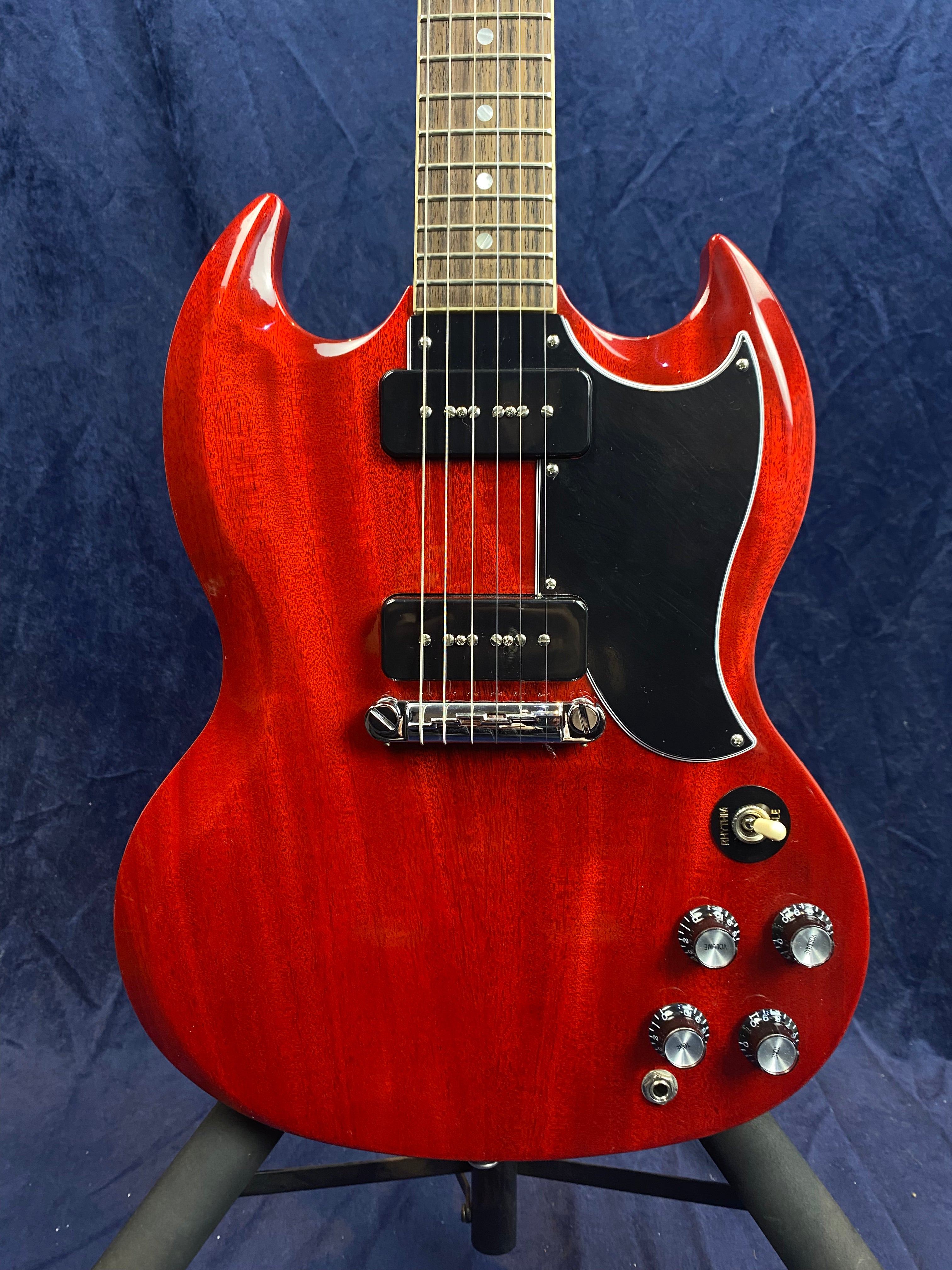 Red electric guitar with a double-cutaway body, black pickguard, two black pickups, four silver control knobs, and a toggle switch.