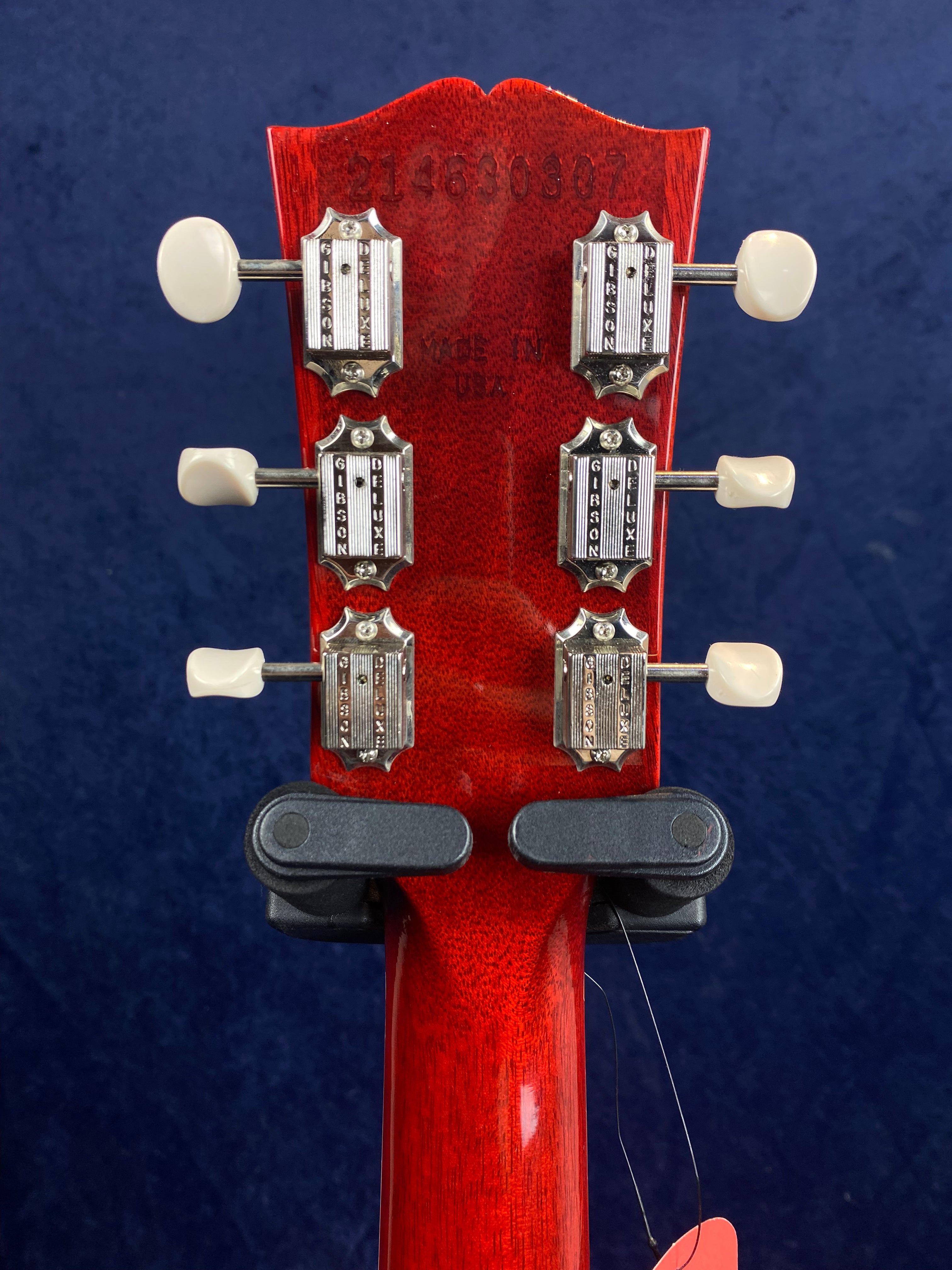 Red Gibson electric guitar headstock back with six vintage-style silver tuning keys and “Made in USA” plus a serial number stamped above.