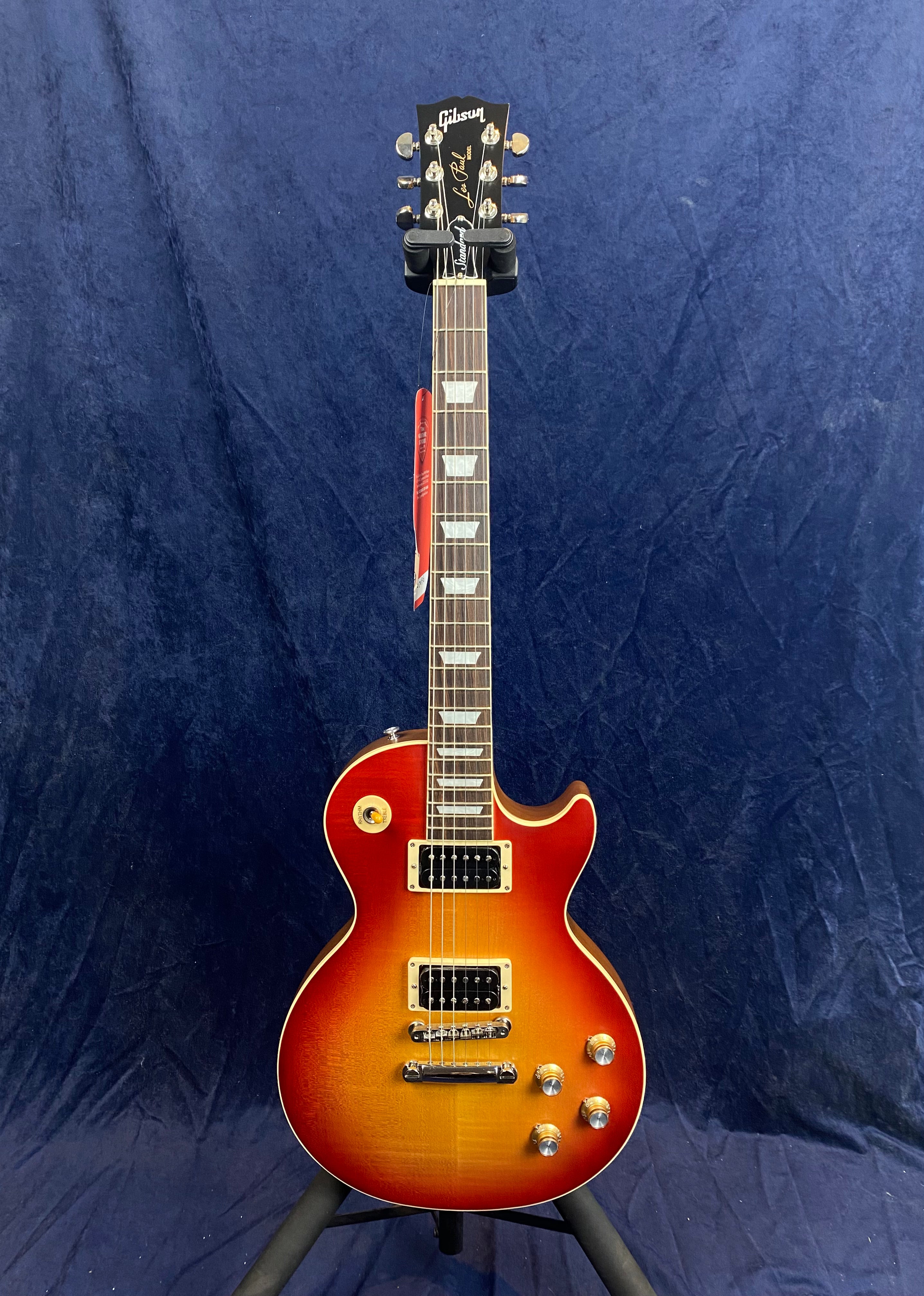 Sunburst electric guitar with a single cutaway body, two humbucker pickups, four control knobs, and trapezoid inlays on a dark fretboard.