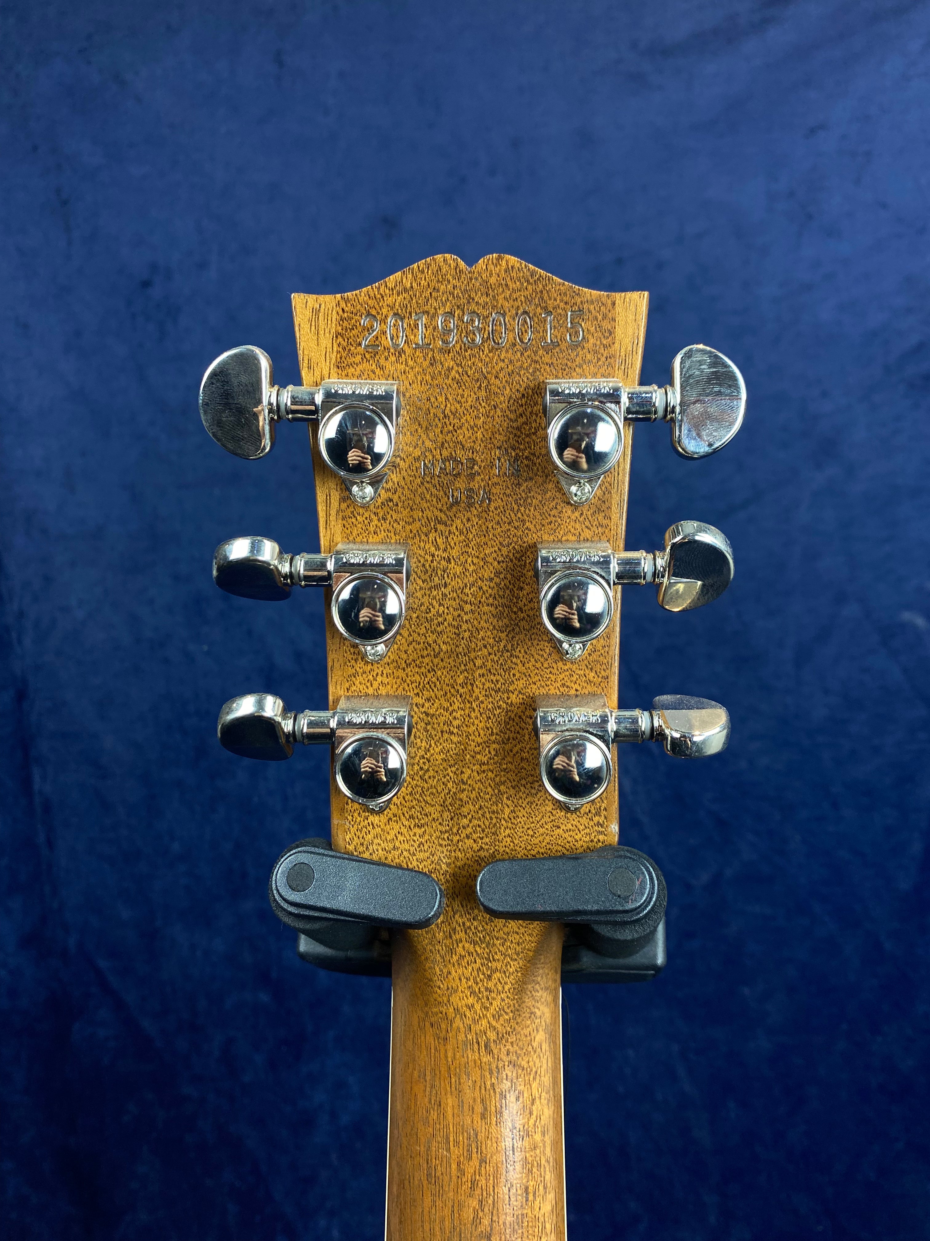 Six chrome tuning pegs on a wooden electric guitar headstock, serial number 201980015 stamped at the top, “Made in USA” text below.