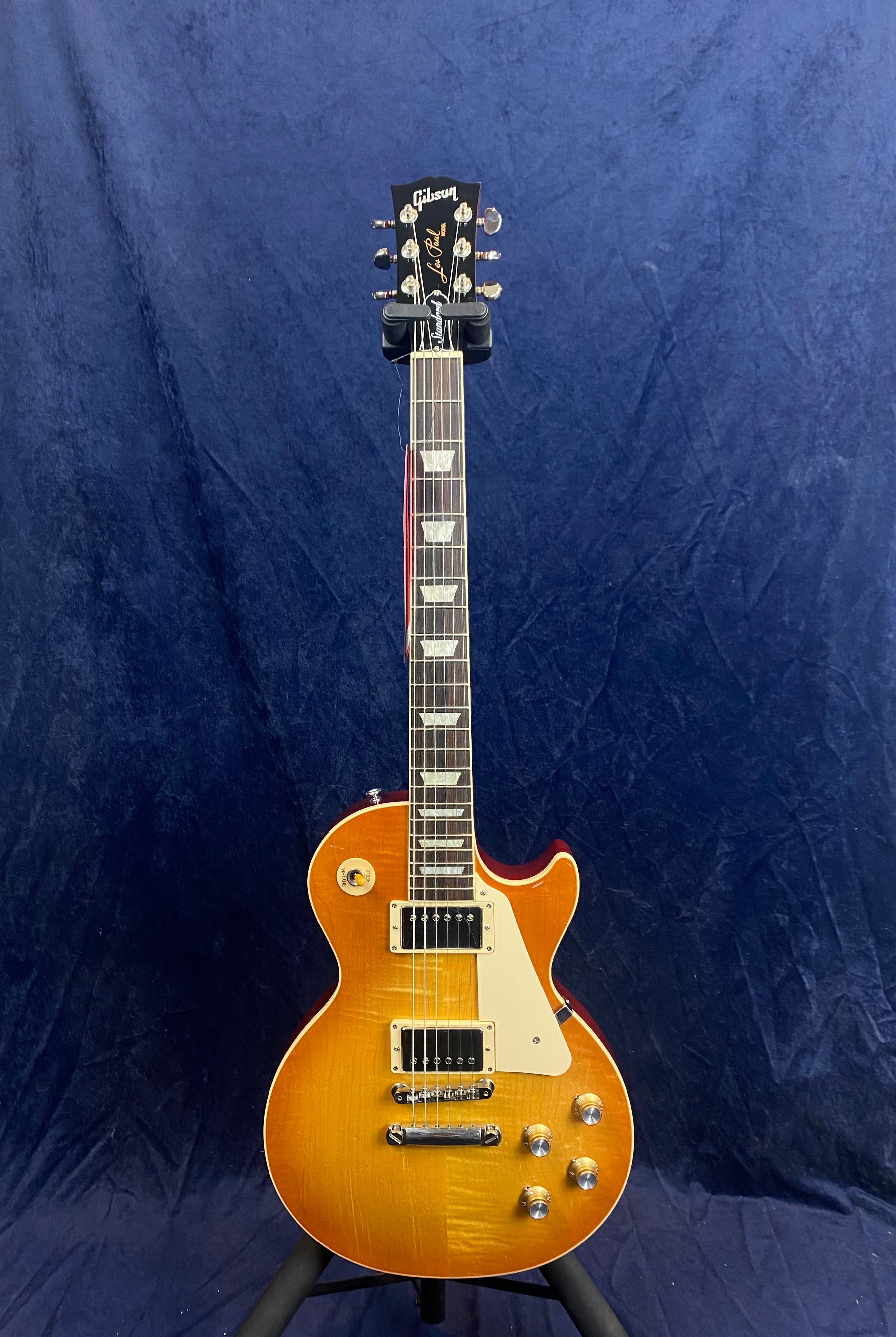 Sunburst-finish Gibson Les Paul electric guitar with cream pickguard, chrome hardware, four control knobs, and trapezoid inlays on the fretboard.