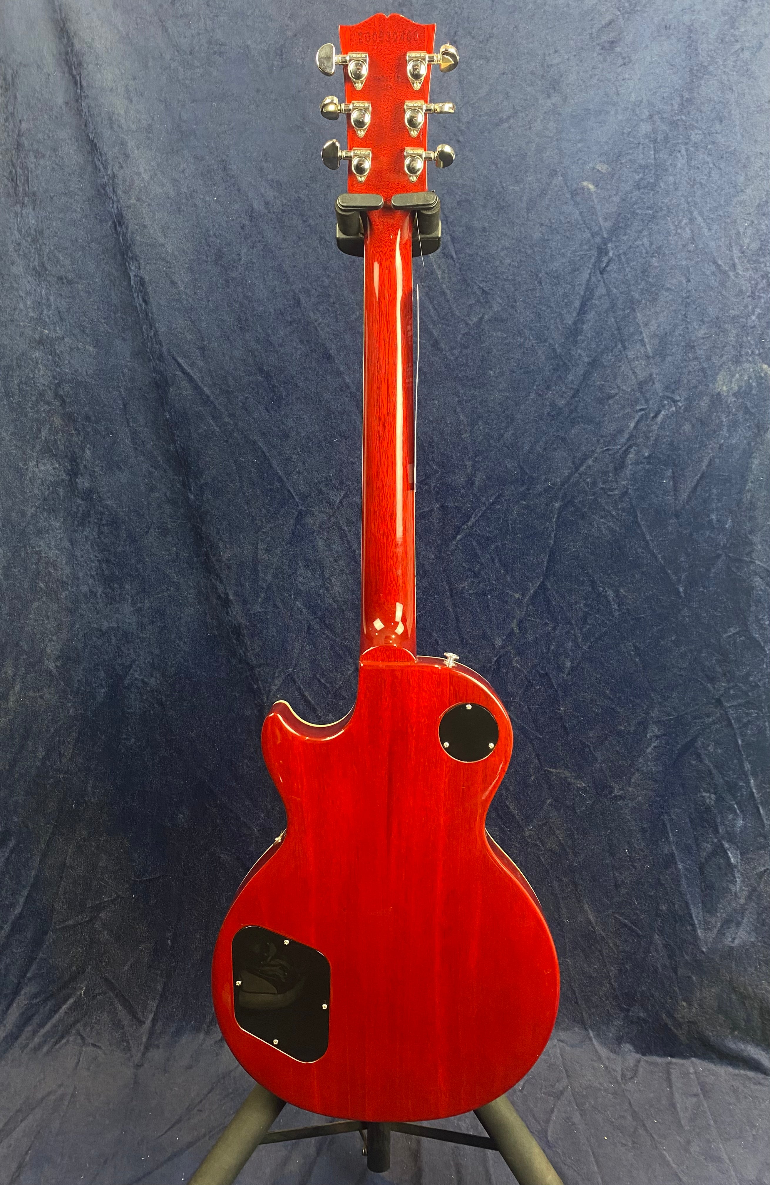 Red electric guitar viewed from the back, showing a glossy finish, two black access panels on the body, and six chrome tuning pegs on the headstock.