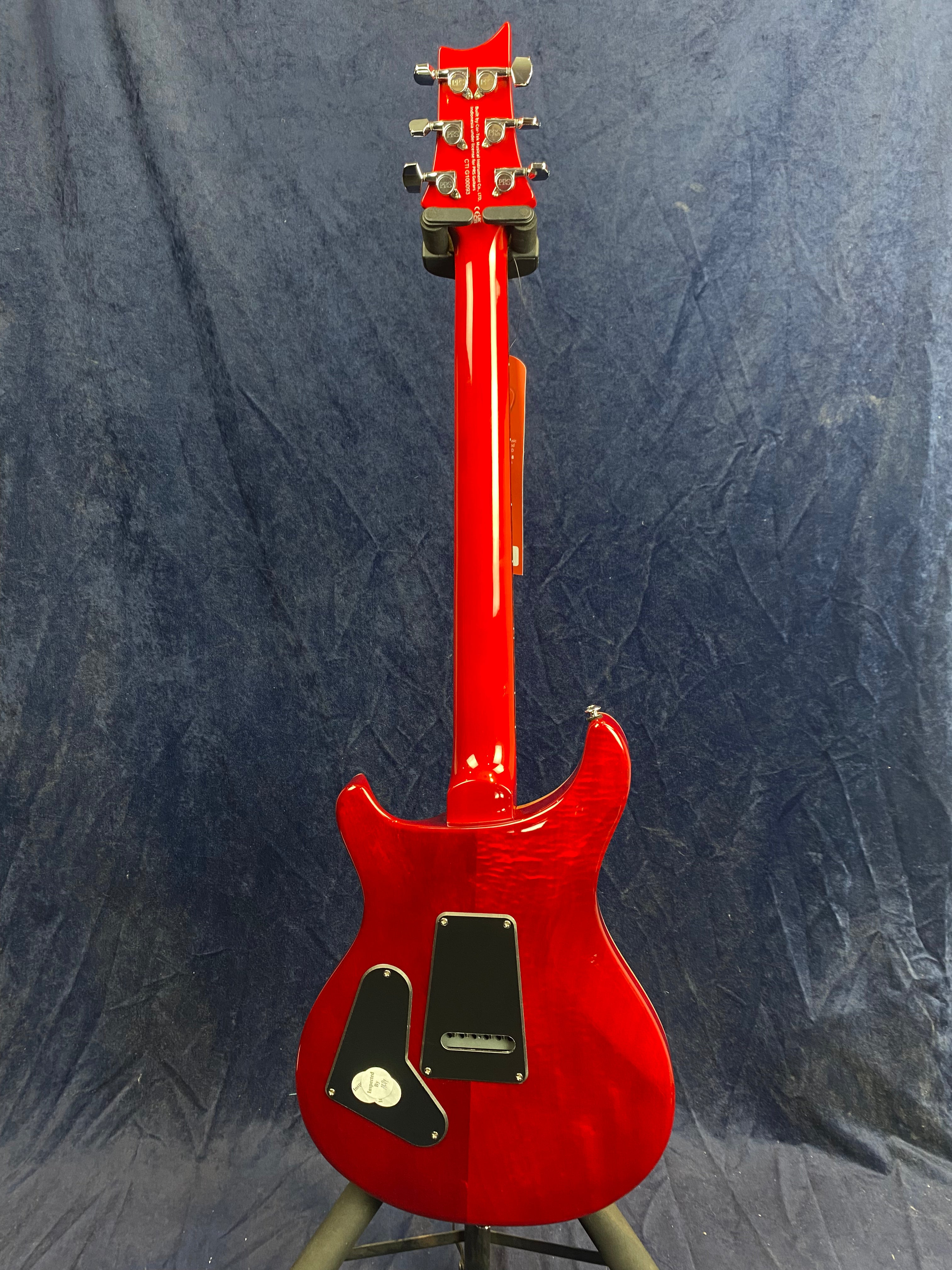 A glossy red electric guitar shown from the back, with a contoured body, two black cavity covers, and six chrome tuning pegs on the headstock.