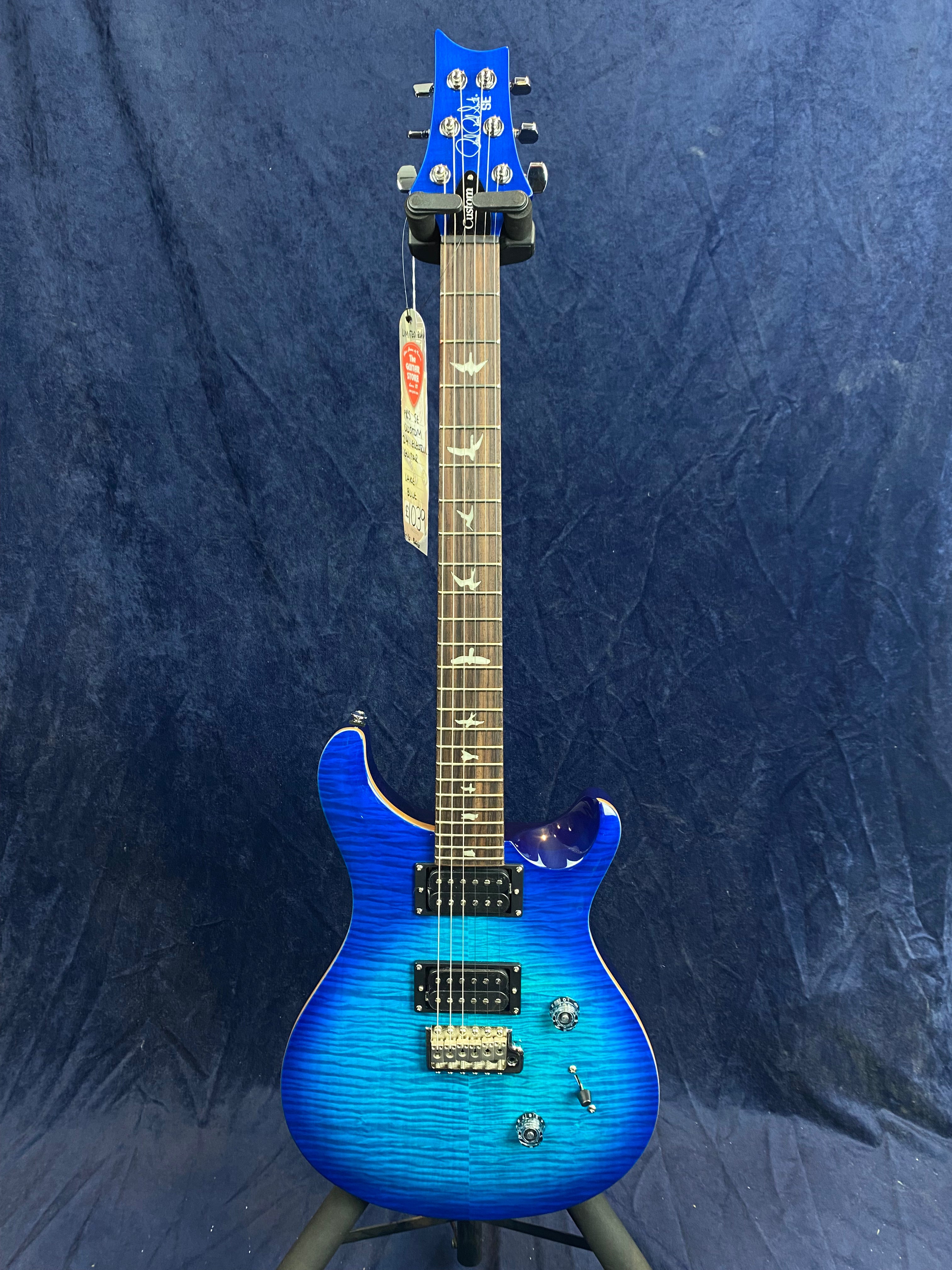 Electric guitar with a bright blue finish, double cutaway body, two humbucker pickups, bird-shaped inlays on the fretboard, and chrome hardware.