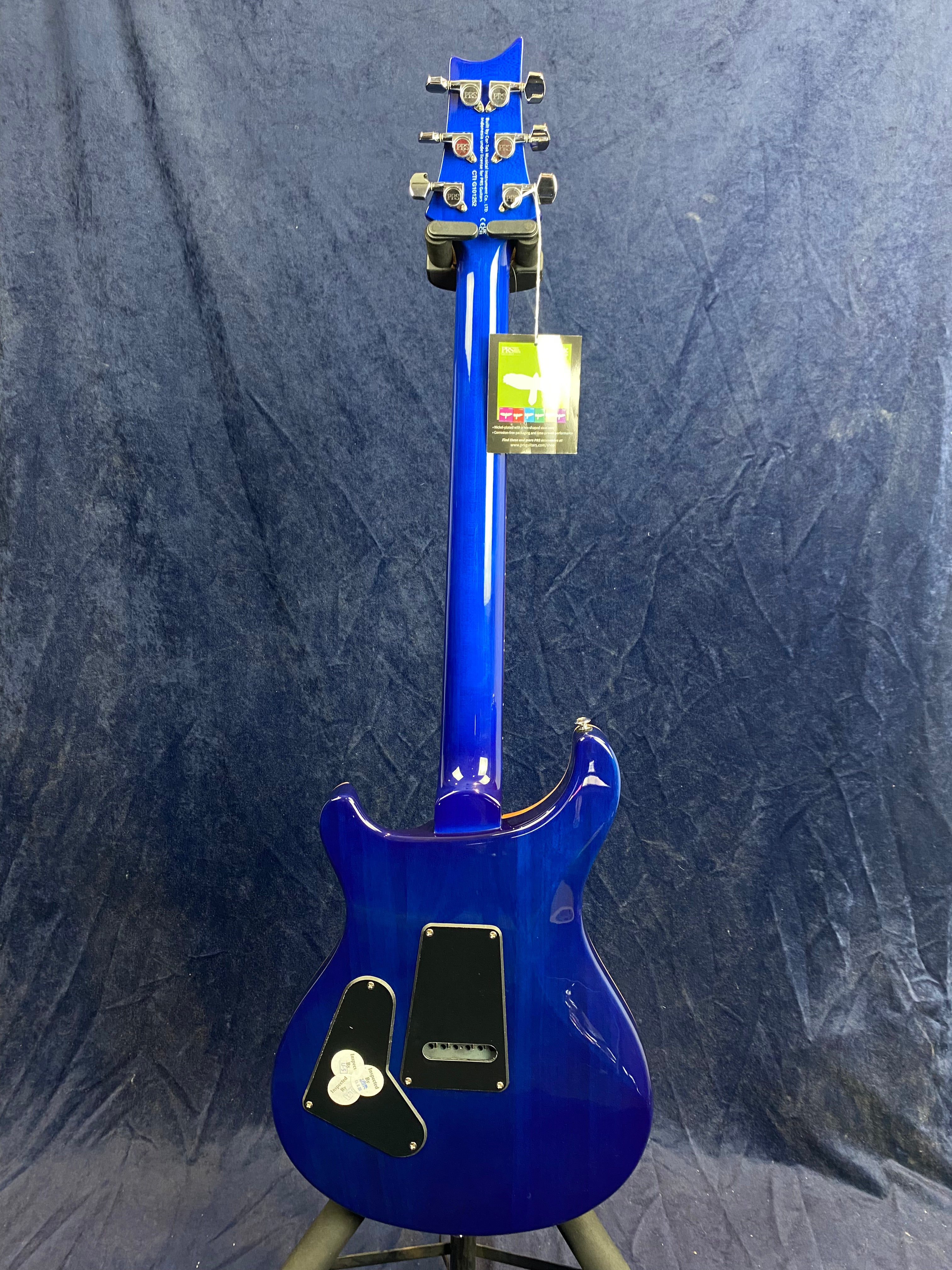 Blue electric guitar shown from the back, with two black access panels on the body and a tag hanging from the headstock.