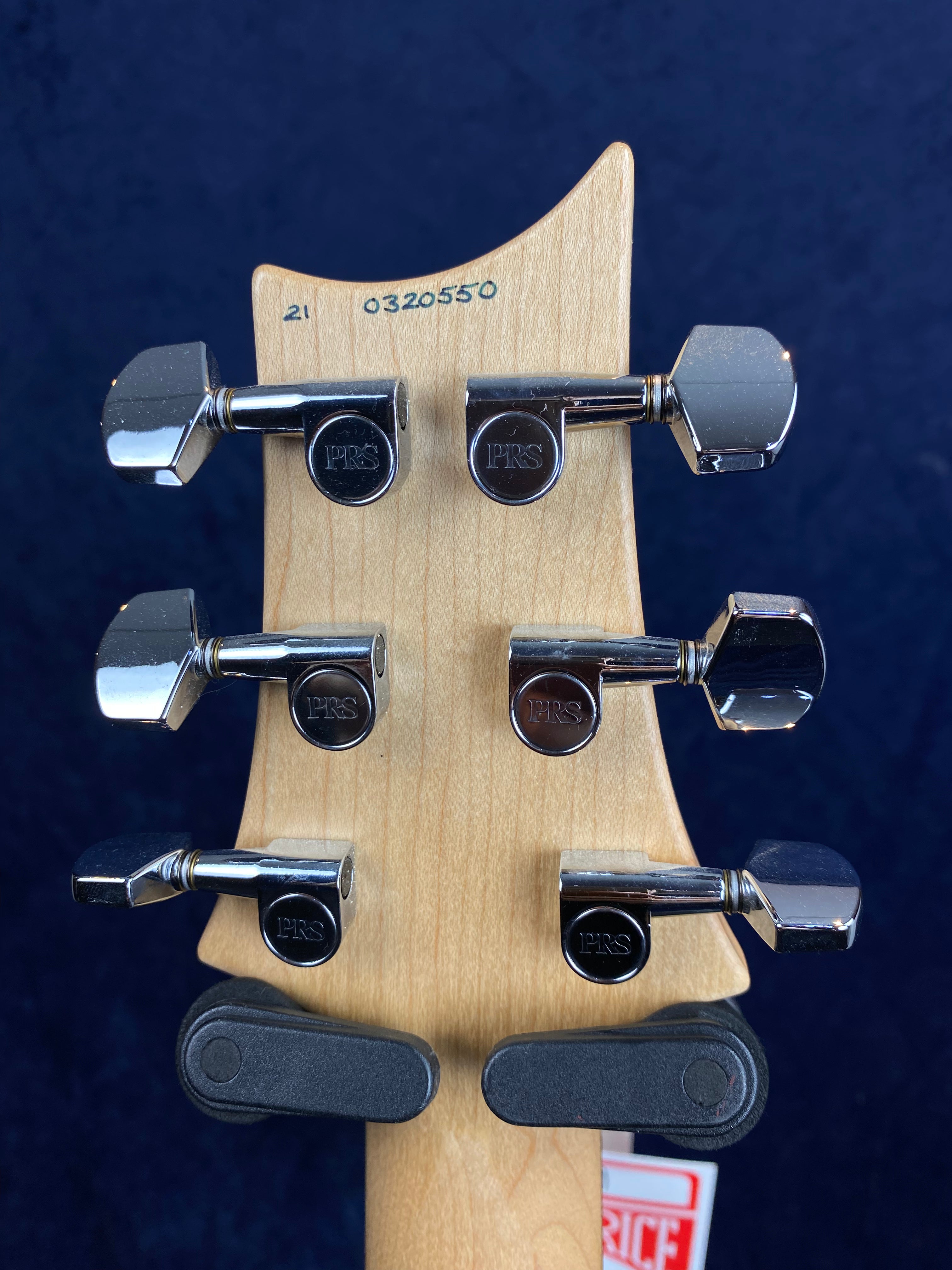Back of an electric guitar headstock showing six chrome PRS tuning pegs and a serial number 0320550 stamped on the light wood.