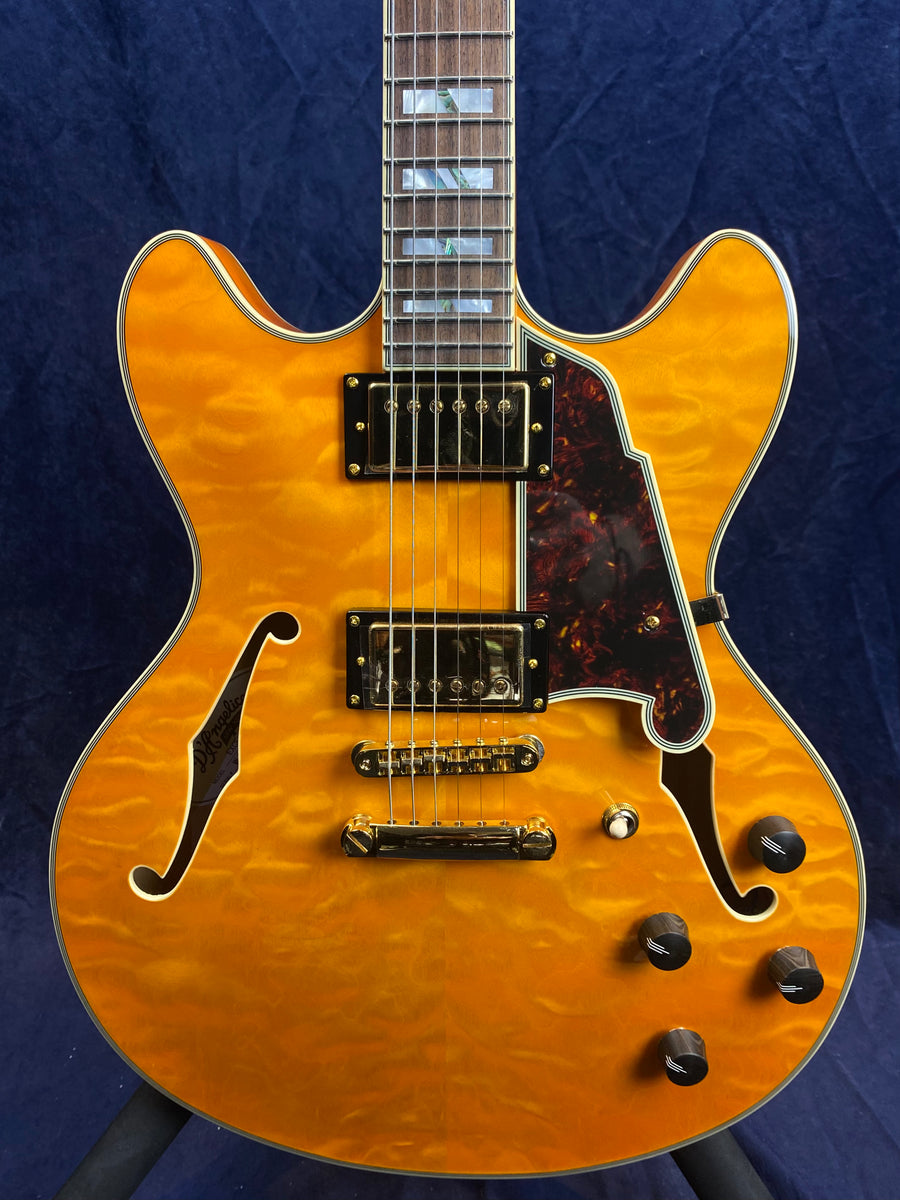 Semi-hollow electric guitar with a glossy amber quilted maple top, gold hardware, two pickups, brown pickguard, and four black control knobs.