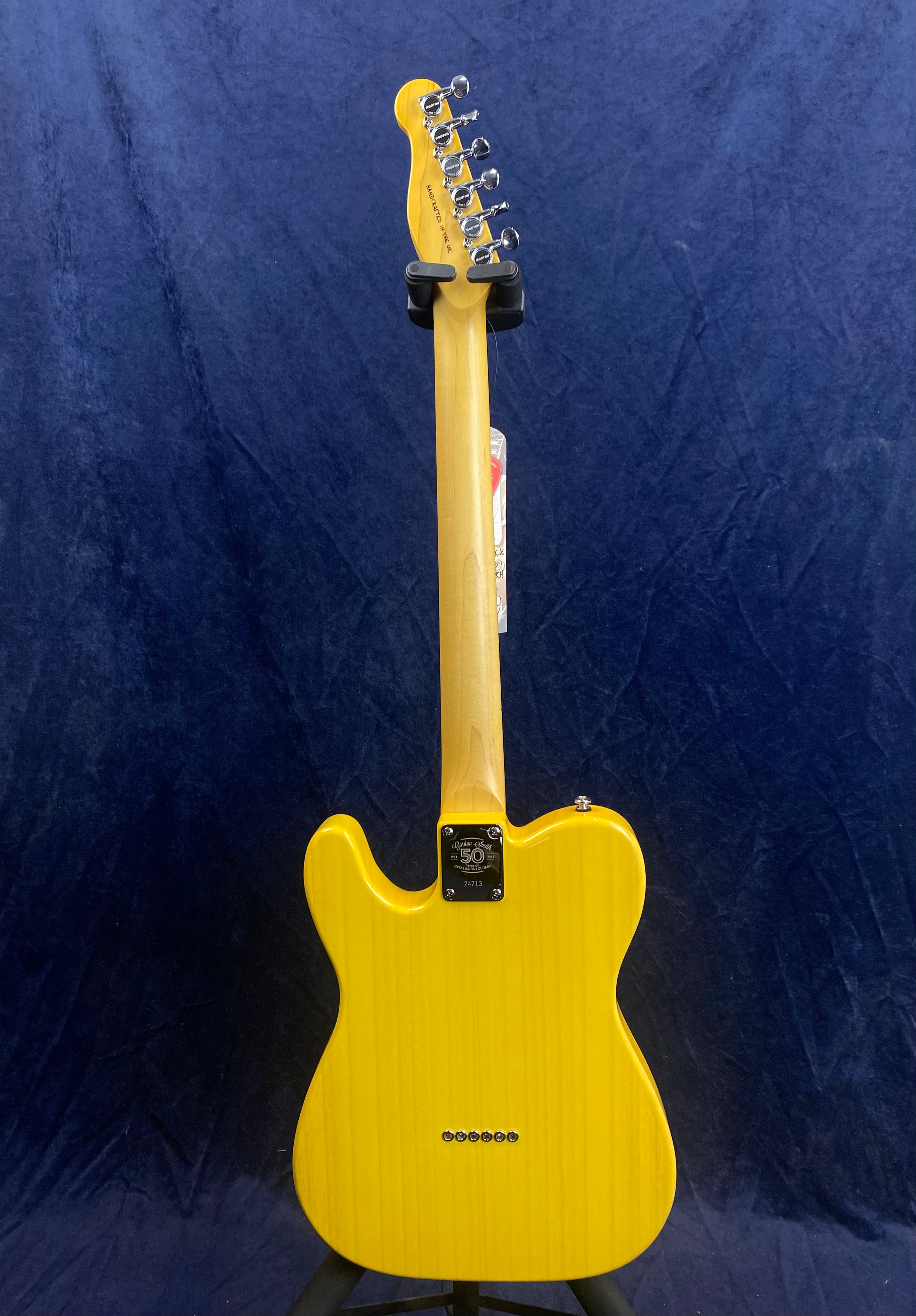 Bright yellow electric guitar, viewed from the back, with a natural wood neck and a metal plate on the body reading "50th Anniversary 2013."