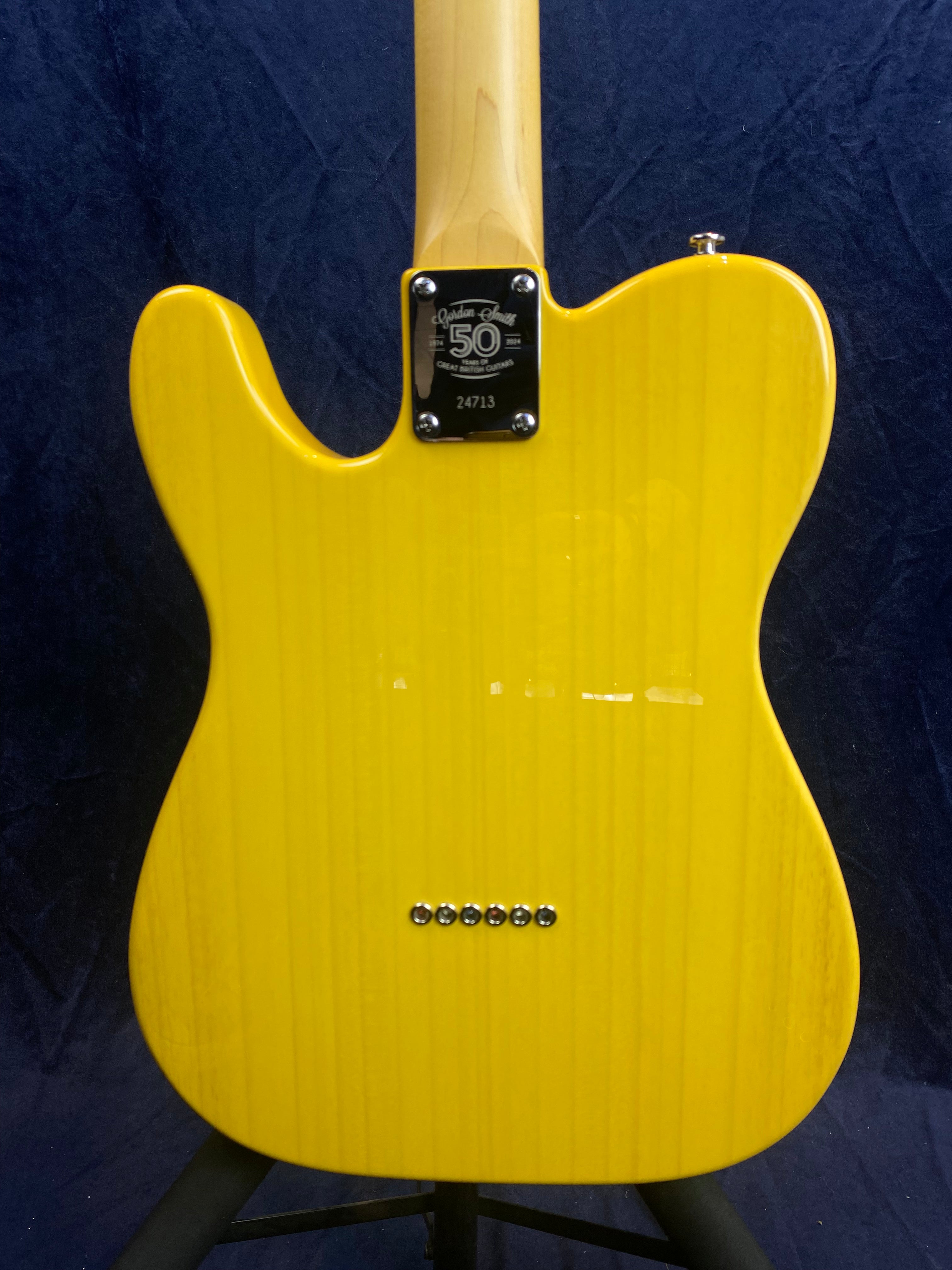 Yellow electric guitar back with a 50th anniversary neck plate and six bridge ferrules in a row near the lower center.