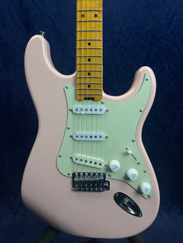 Pink electric guitar with a light green pickguard, three white single-coil pickups, three white control knobs, and a maple neck with dot inlays.