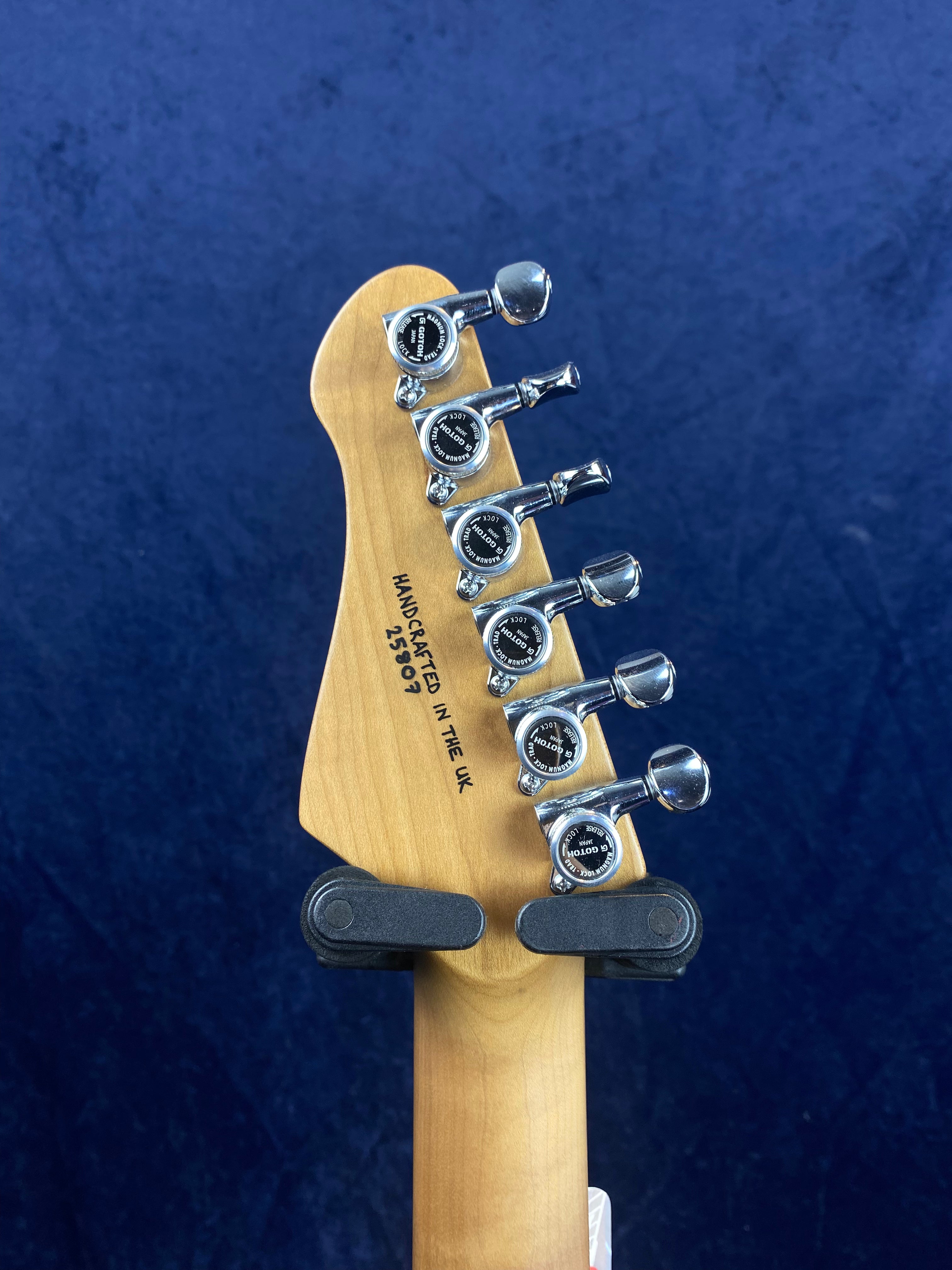 Six chrome tuning pegs on the back of a light wood electric guitar headstock, with "Handcrafted in the UK" stamped in black text.