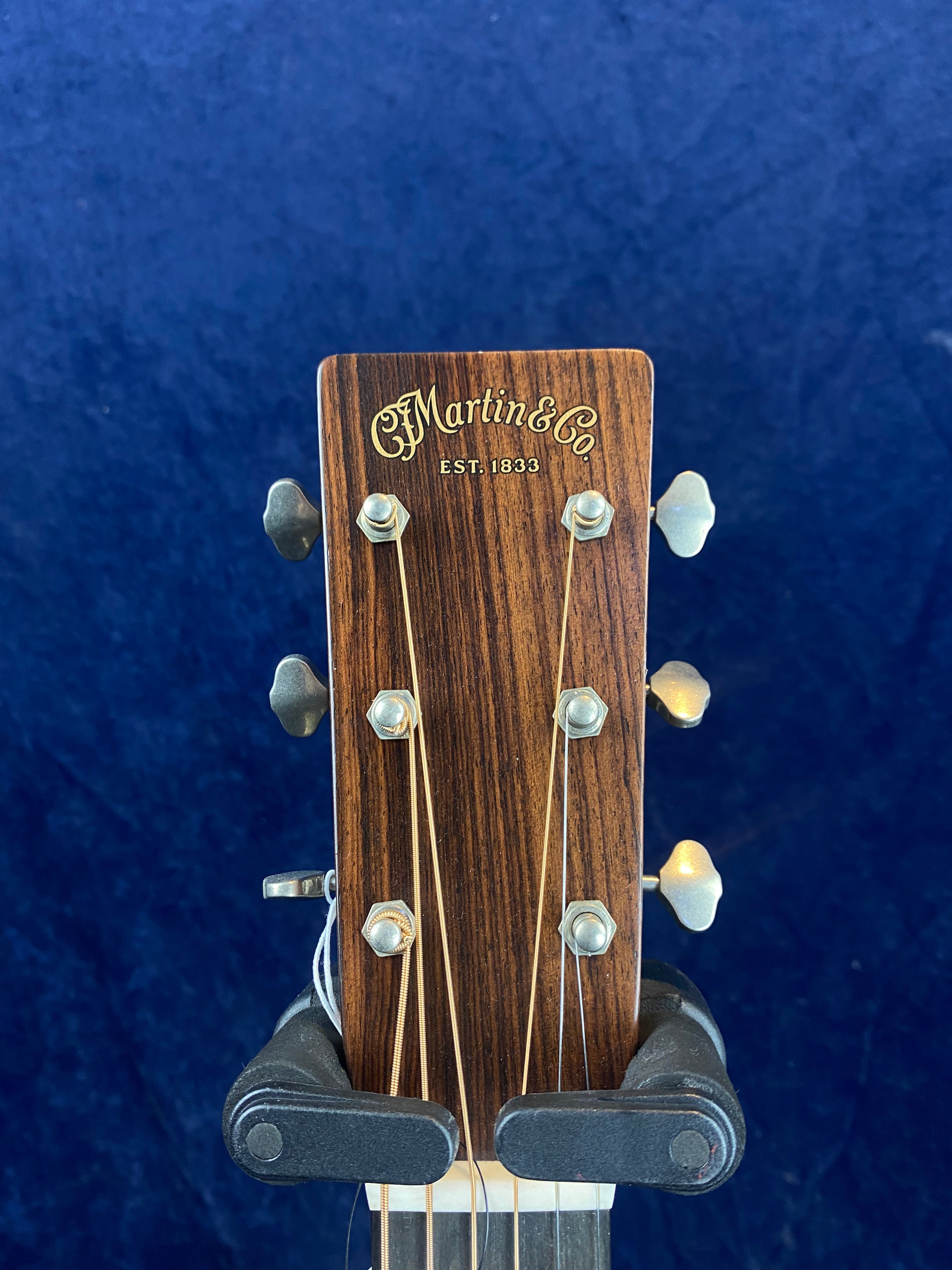 Close-up of a Martin & Co. acoustic guitar headstock with six tuning pegs and logo in gold lettering on wood grain.