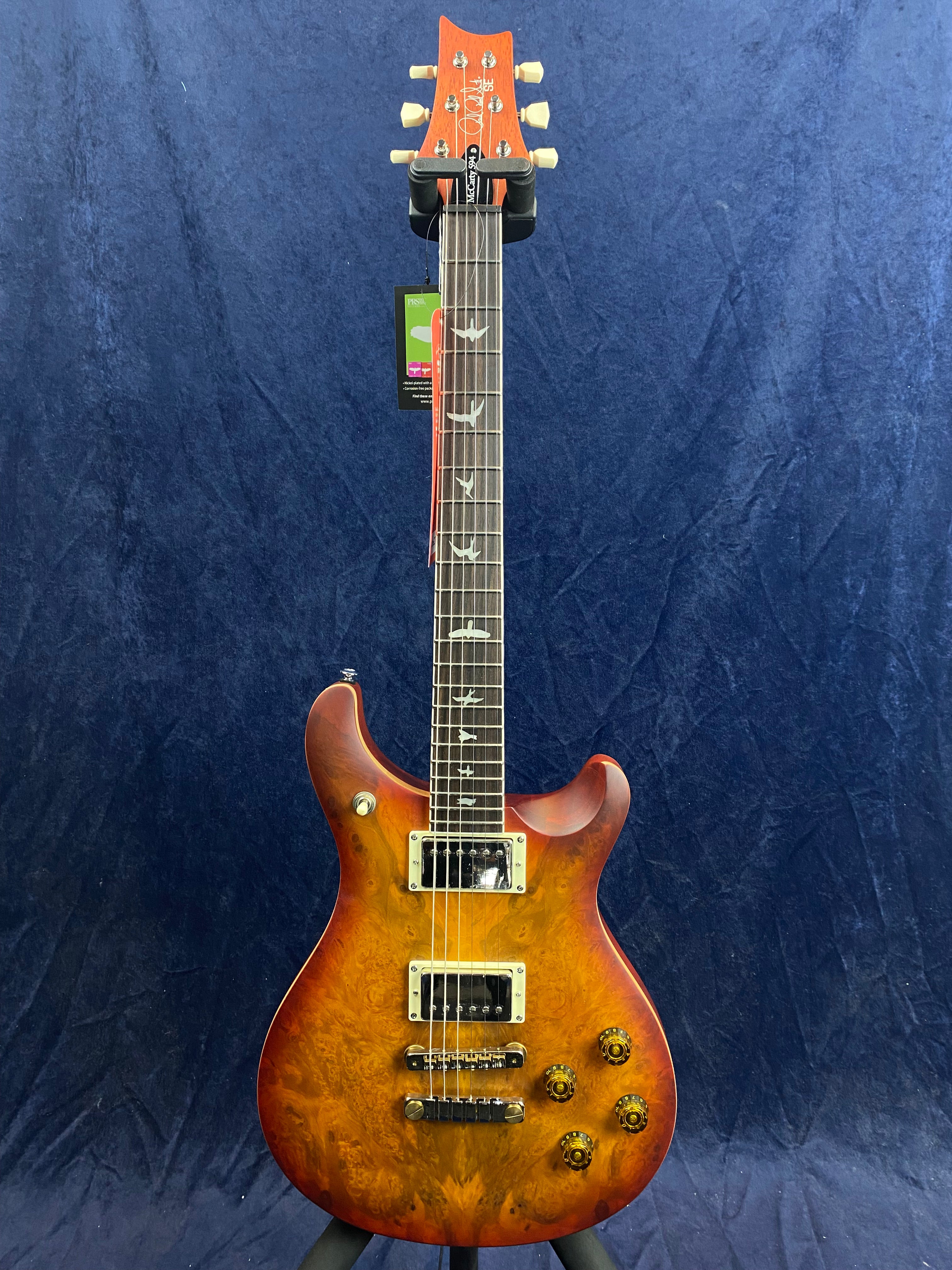 Sunburst electric guitar with a carved wood top, two humbucker pickups, bird inlays on the fretboard, and four gold control knobs.