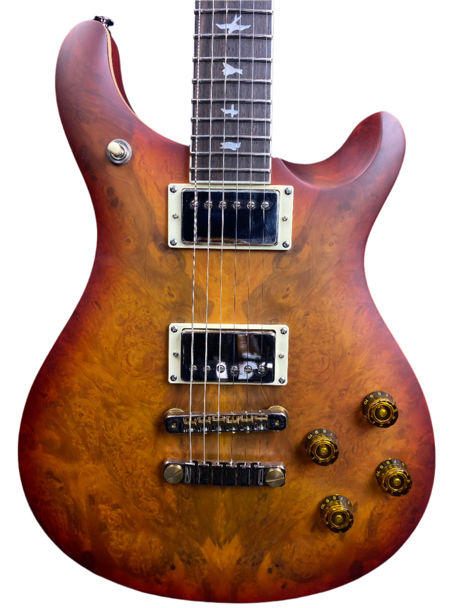 Electric guitar with a glossy reddish-brown wood grain body, two humbucker pickups, four amber control knobs, and bird inlays on the fretboard.