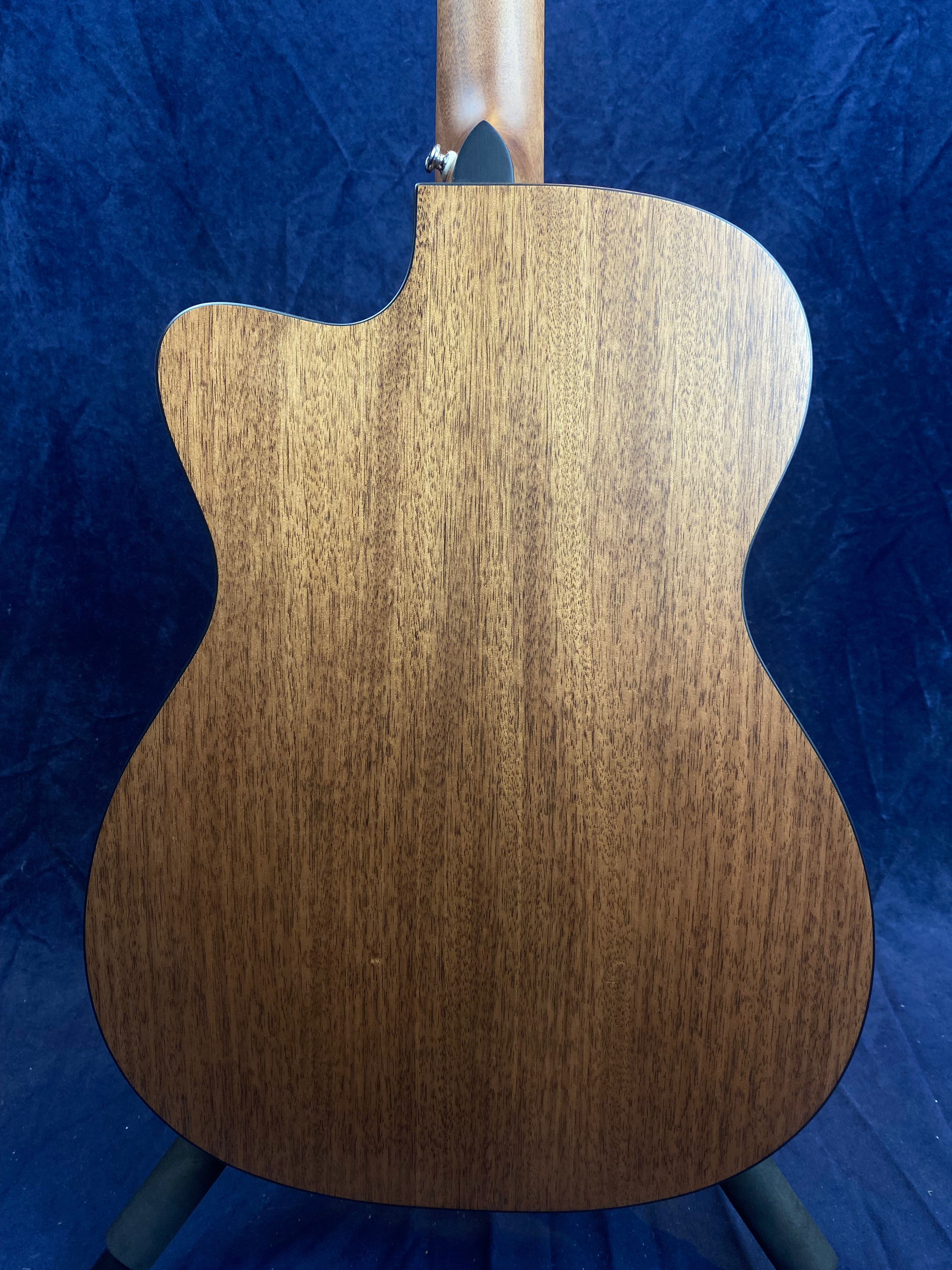 Back view of an acoustic guitar with a smooth, natural wood grain finish, slightly curved body, and a single cutaway near the neck.
